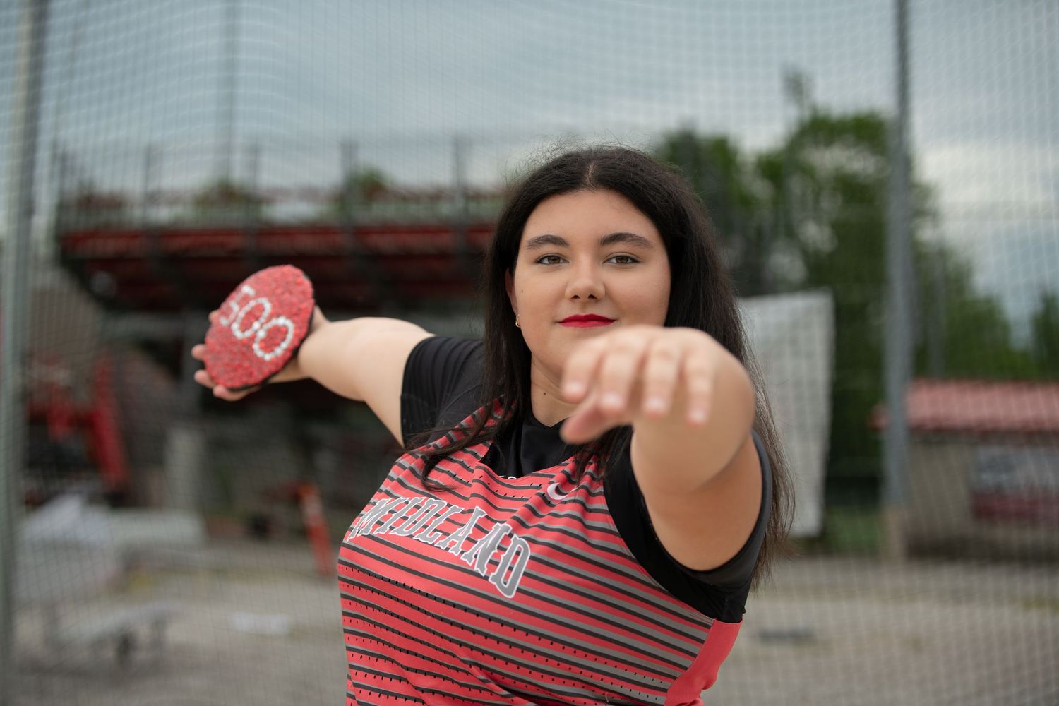 Person in red athletic wear poses with team spirit outdoors.