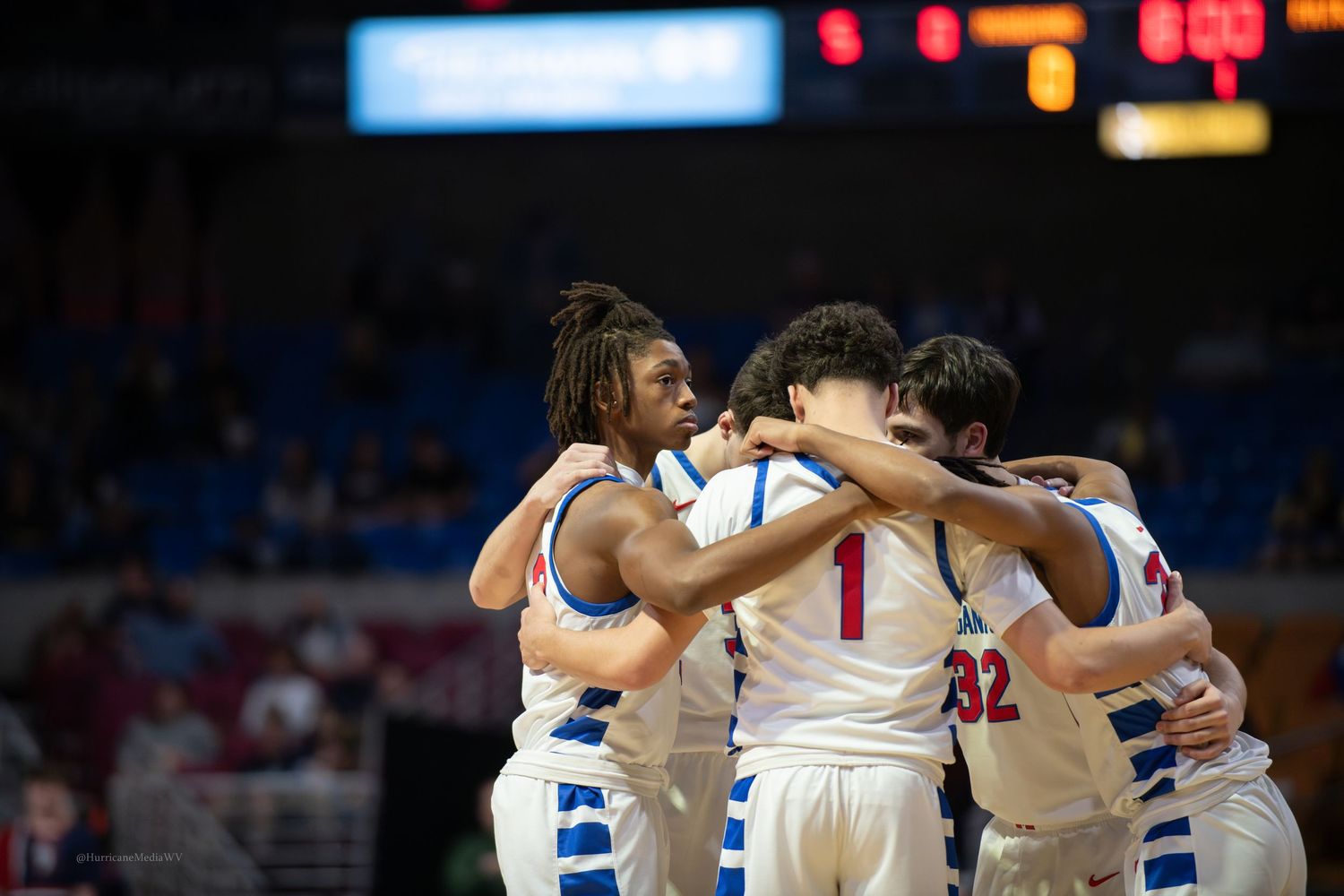 Basketball team huddles together during game showing team unity and support.