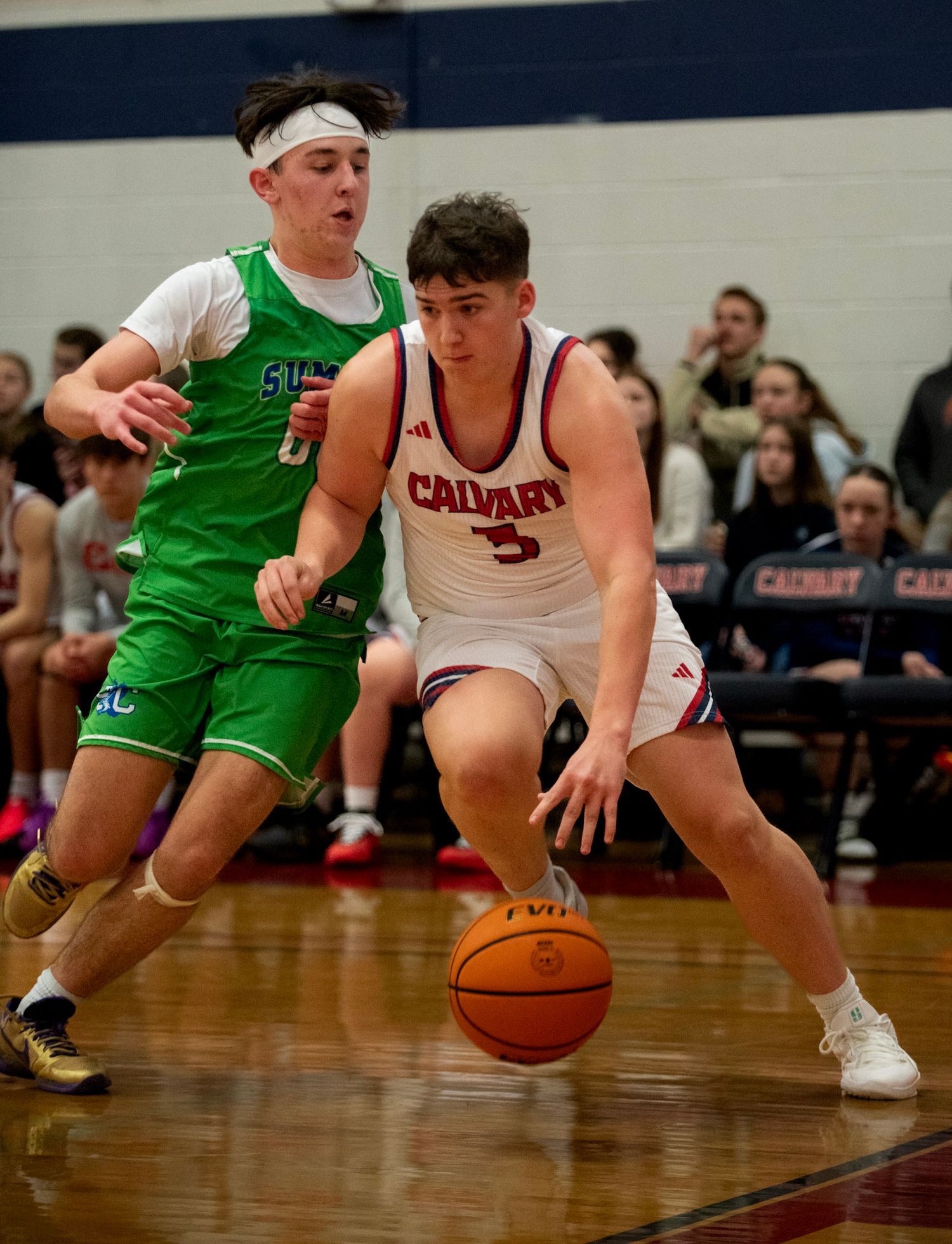 Basketball players scramble for possession of the ball during a game between green and white teams.
