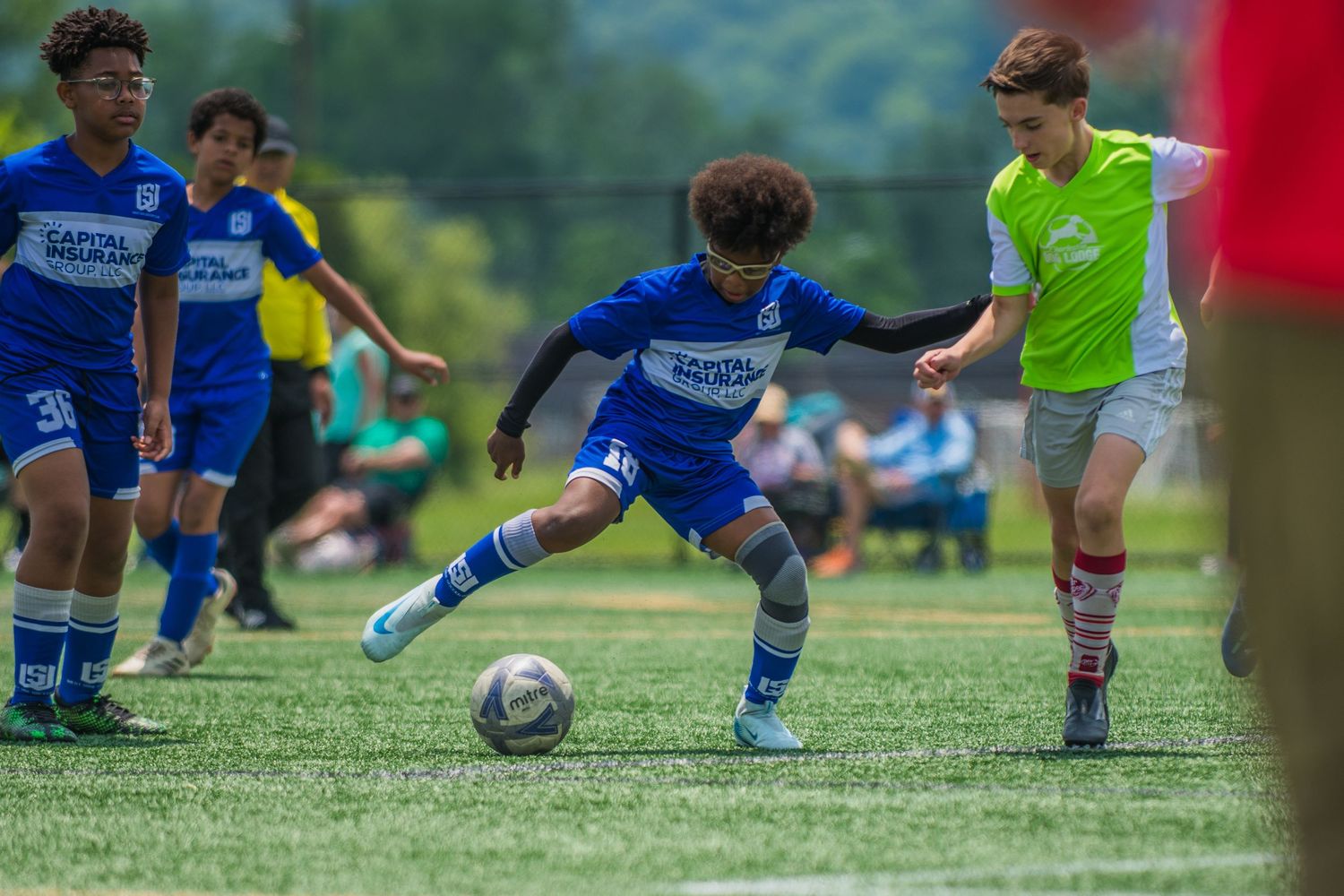 Soccer players compete for possession of the ball on a grassy field.