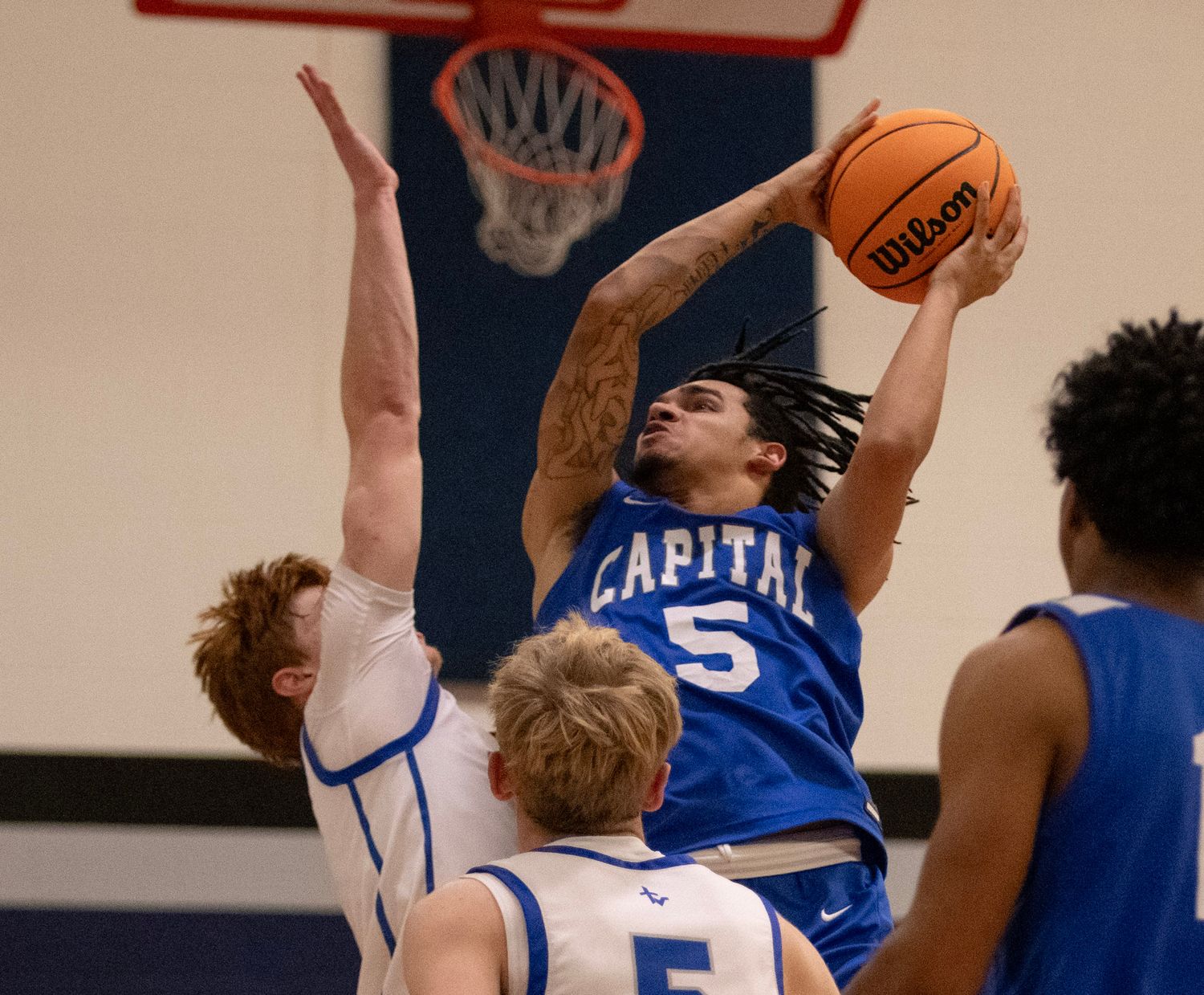 Basketball players compete for possession during an intense game on an indoor court.