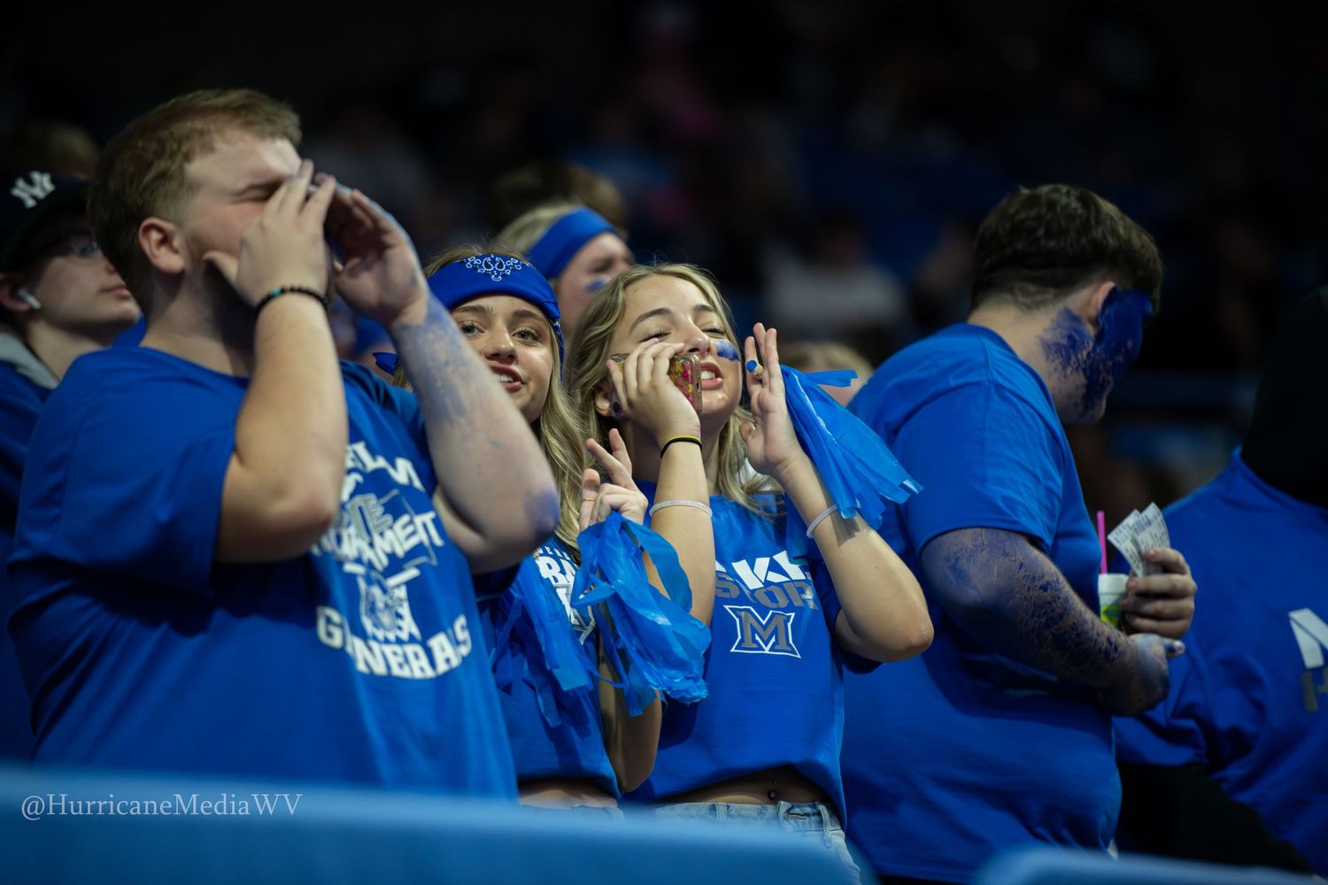 Excited fans in blue jerseys react emotionally during an intense sporting event.