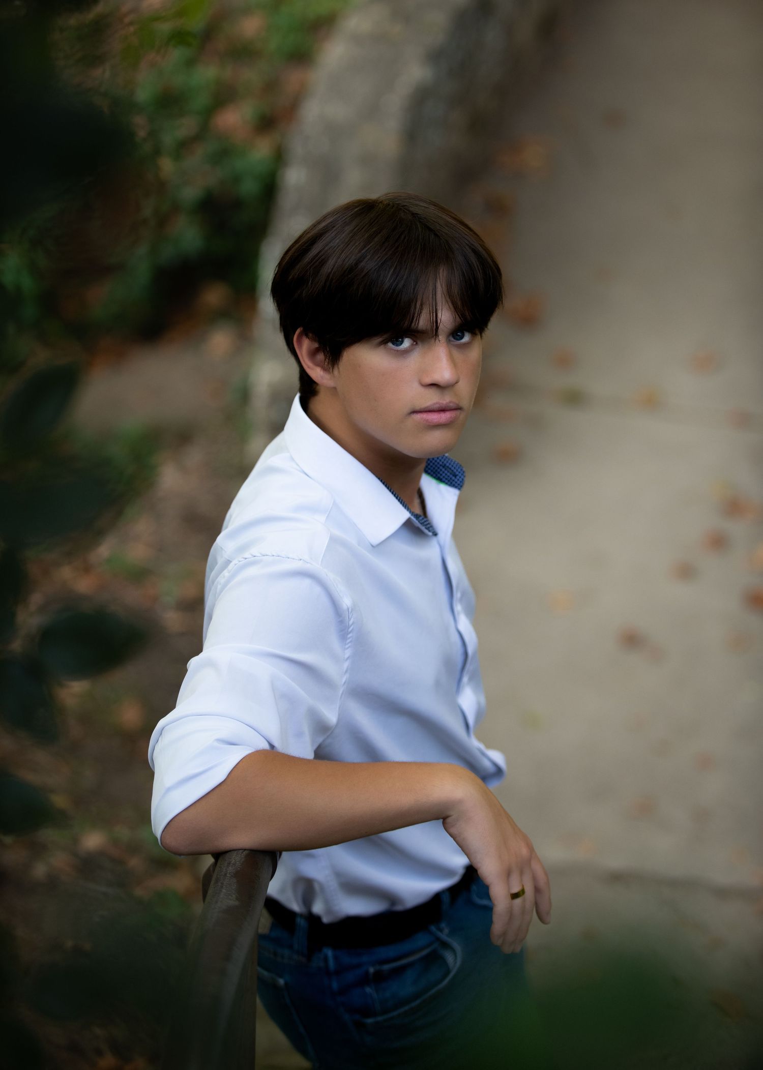 Portrait of someone in a crisp white button-down shirt against a blurred outdoor background.