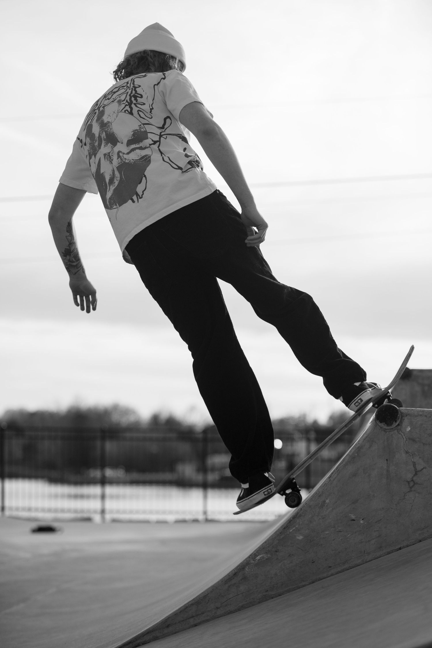 Skateboarder in hoodie performing trick on ramp in black and white photography.