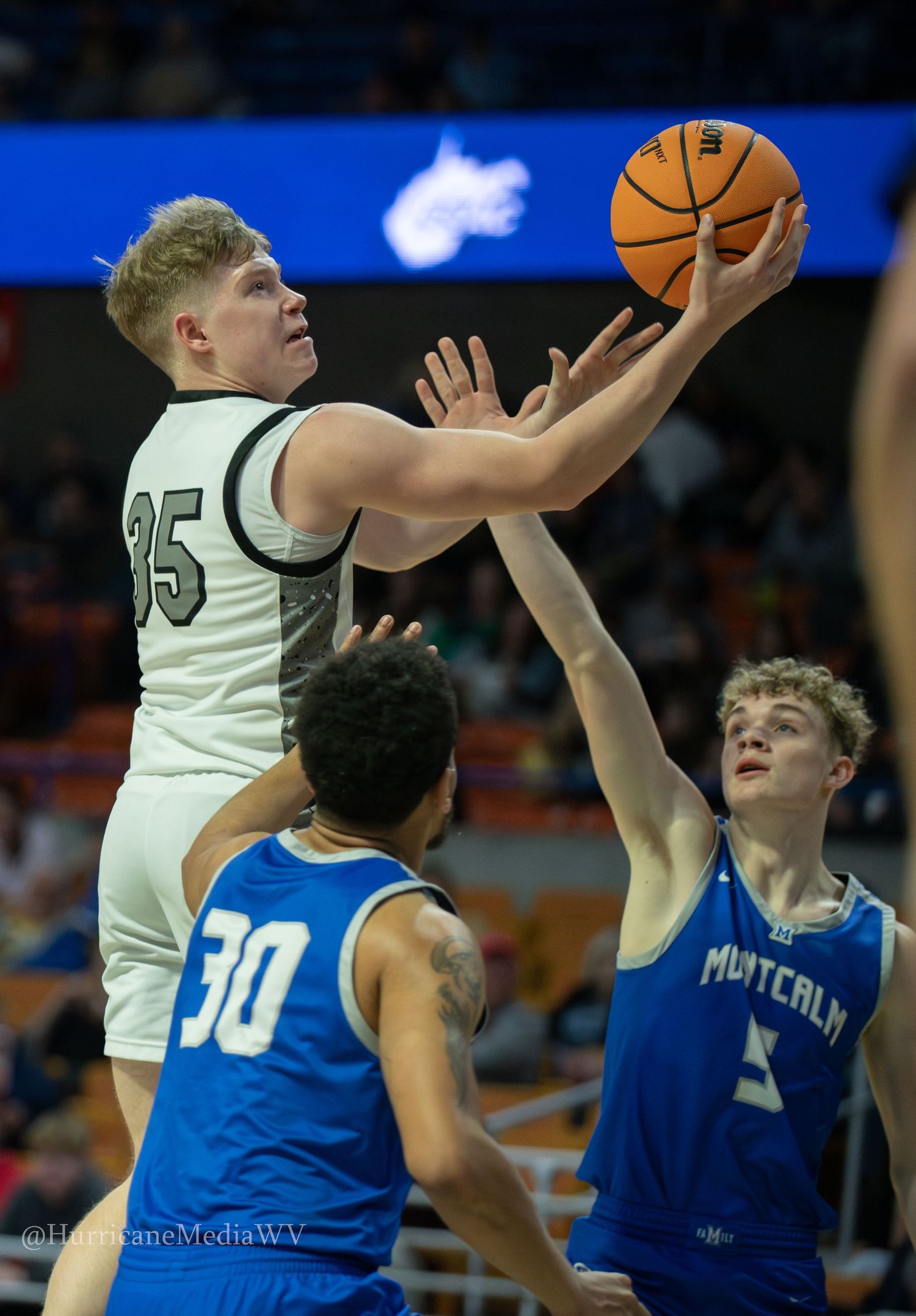 A high school basketball player attempts a layup during an intense game moment.