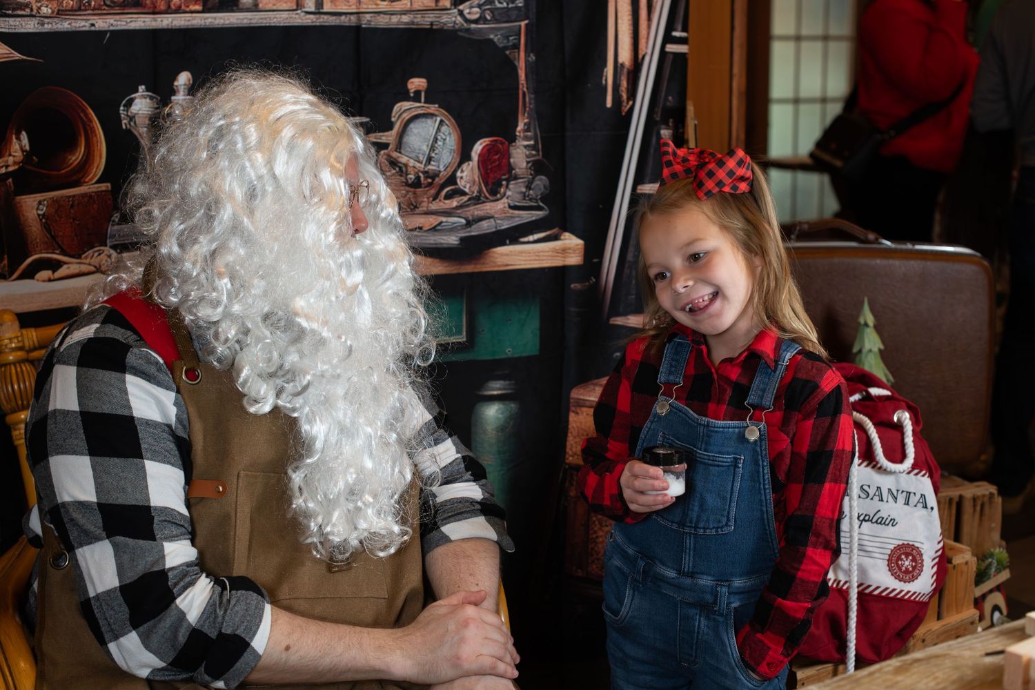 A festive holiday party scene with people gathered around a table wearing casual winter attire and plaid shirts.