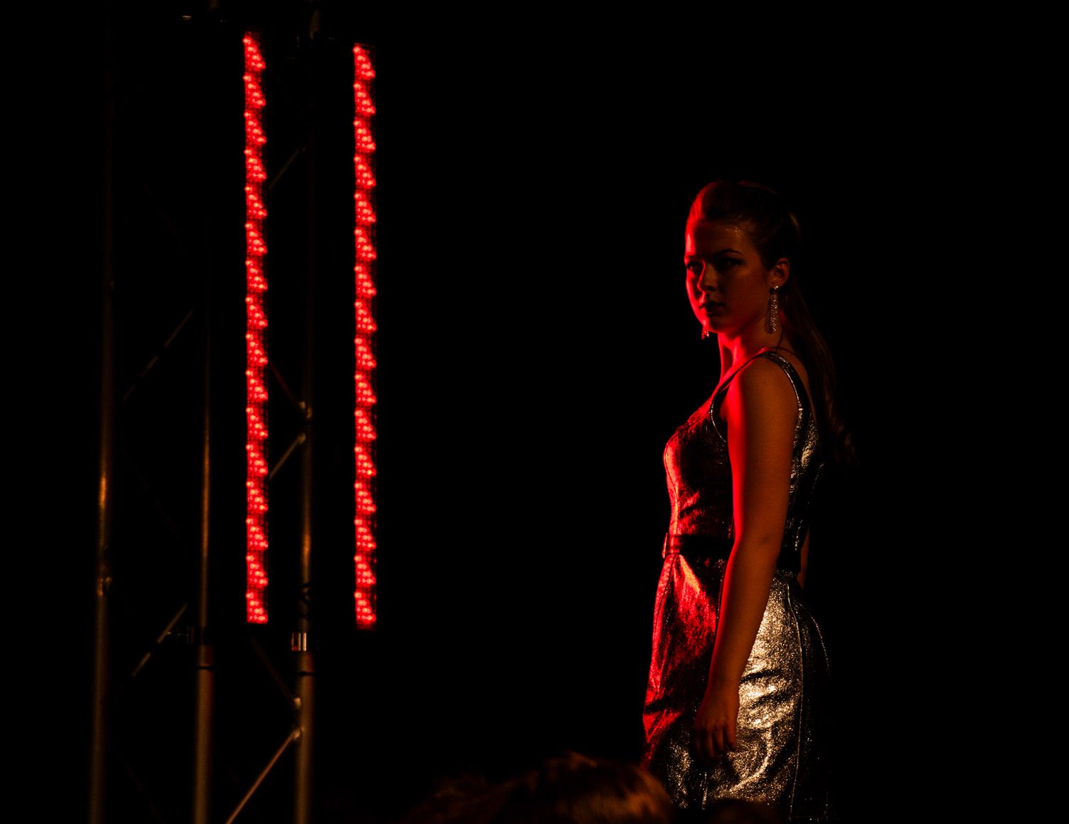 Dramatic silhouette against red stage lighting in performance setting.