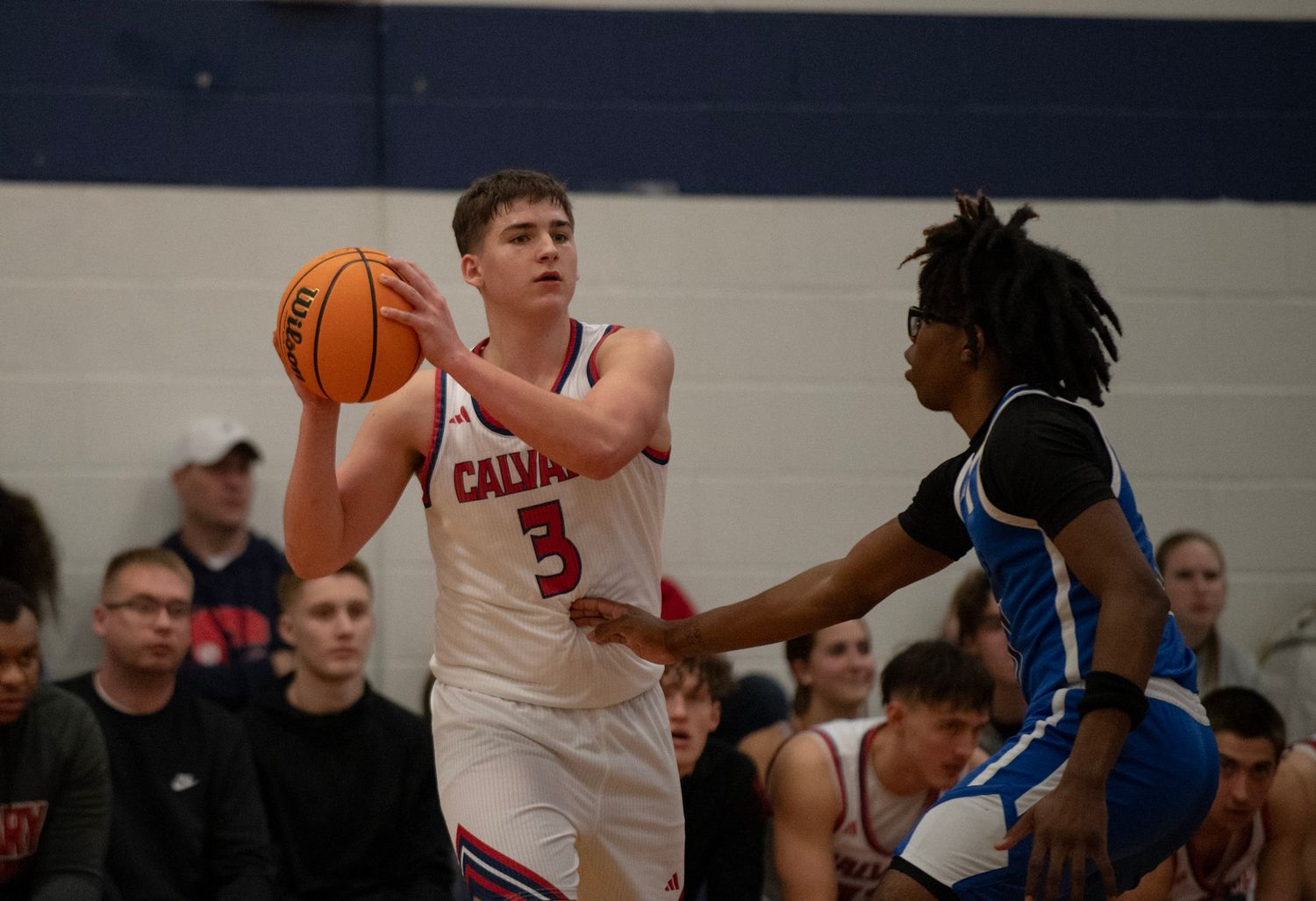 High school basketball players from opposing teams battle for ball possession during game.