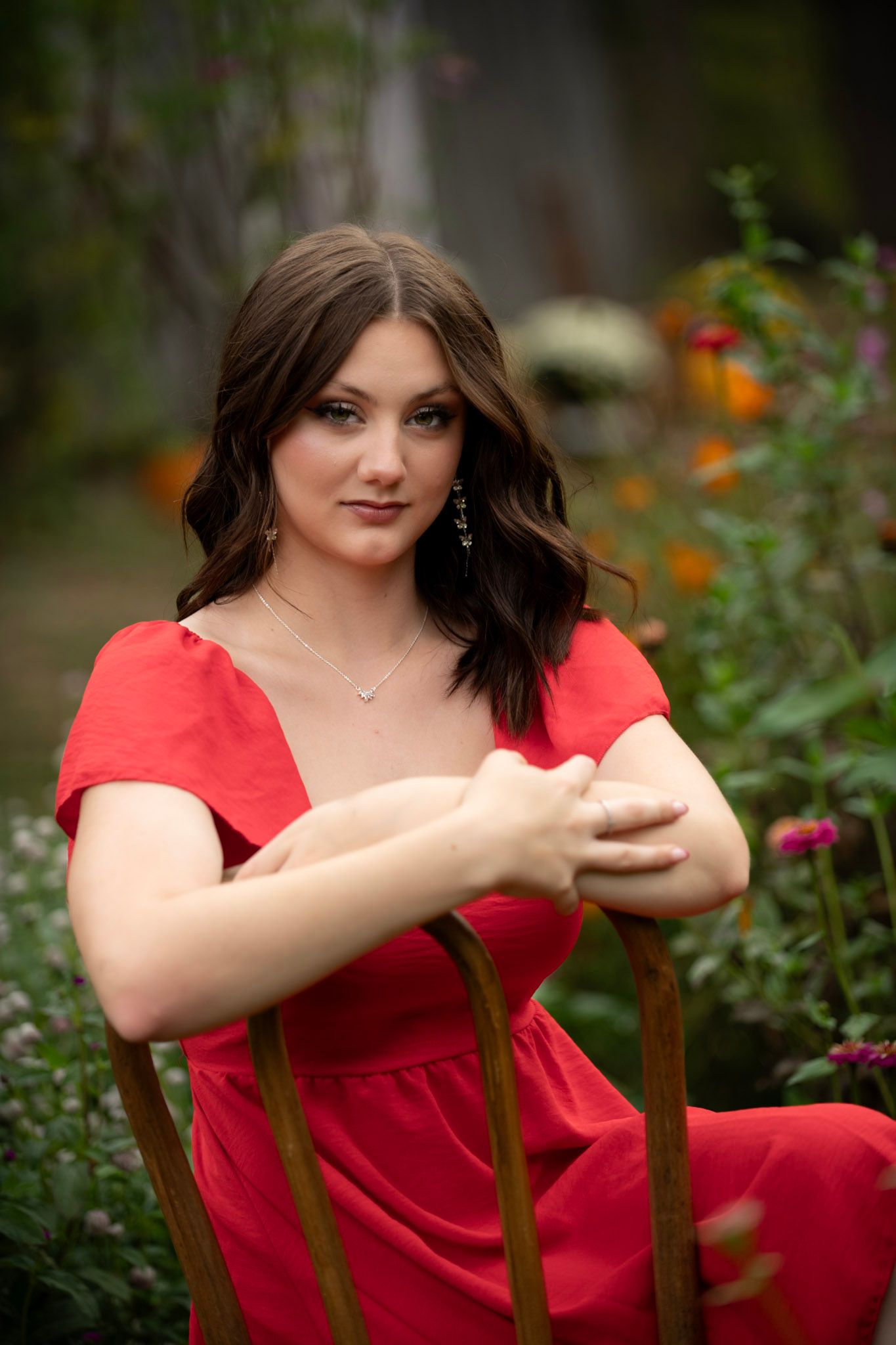 Portrait in red dress surrounded by colorful garden flowers.