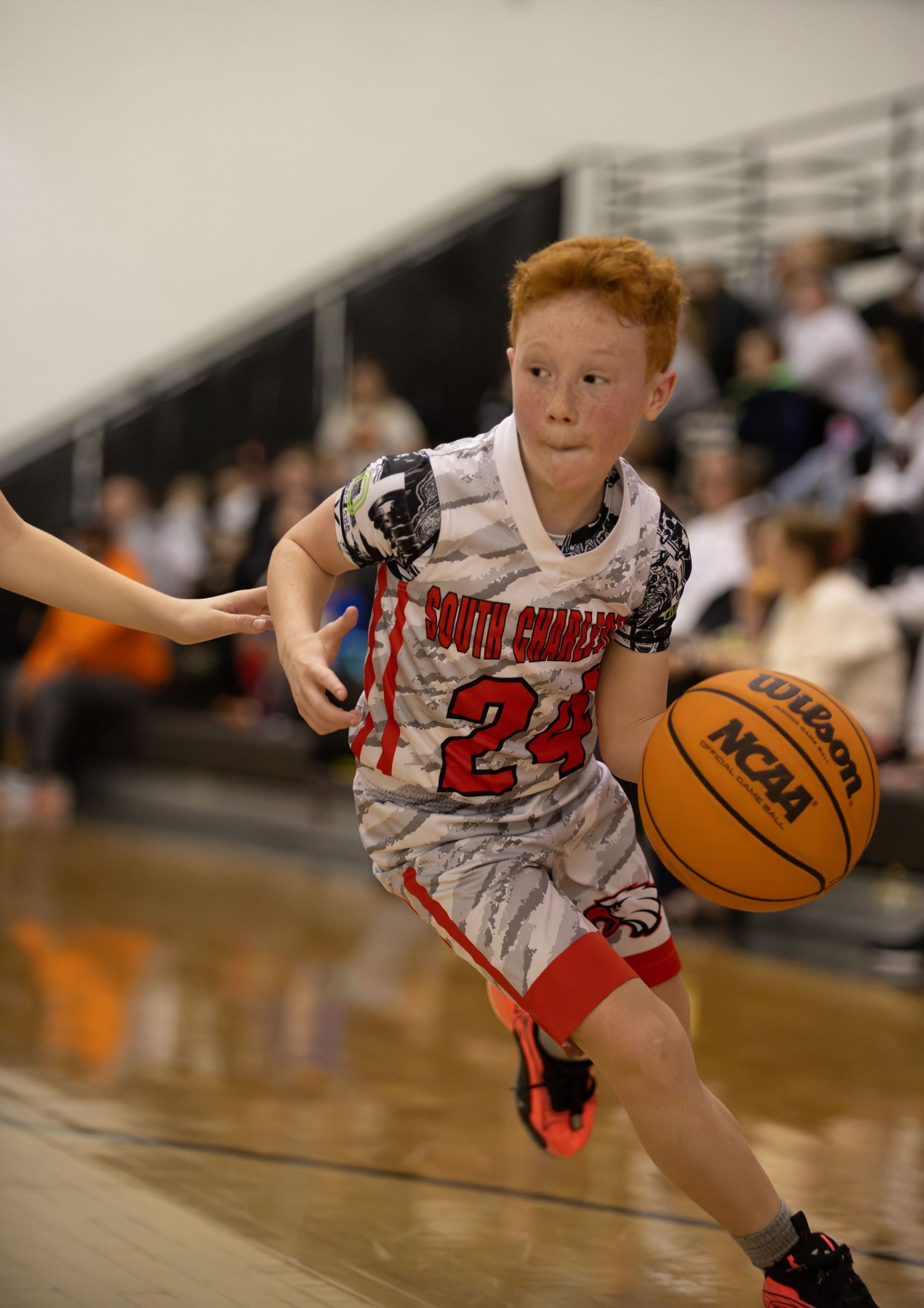 Basketball player in white jersey number 24 dribbles past defender during indoor game.
