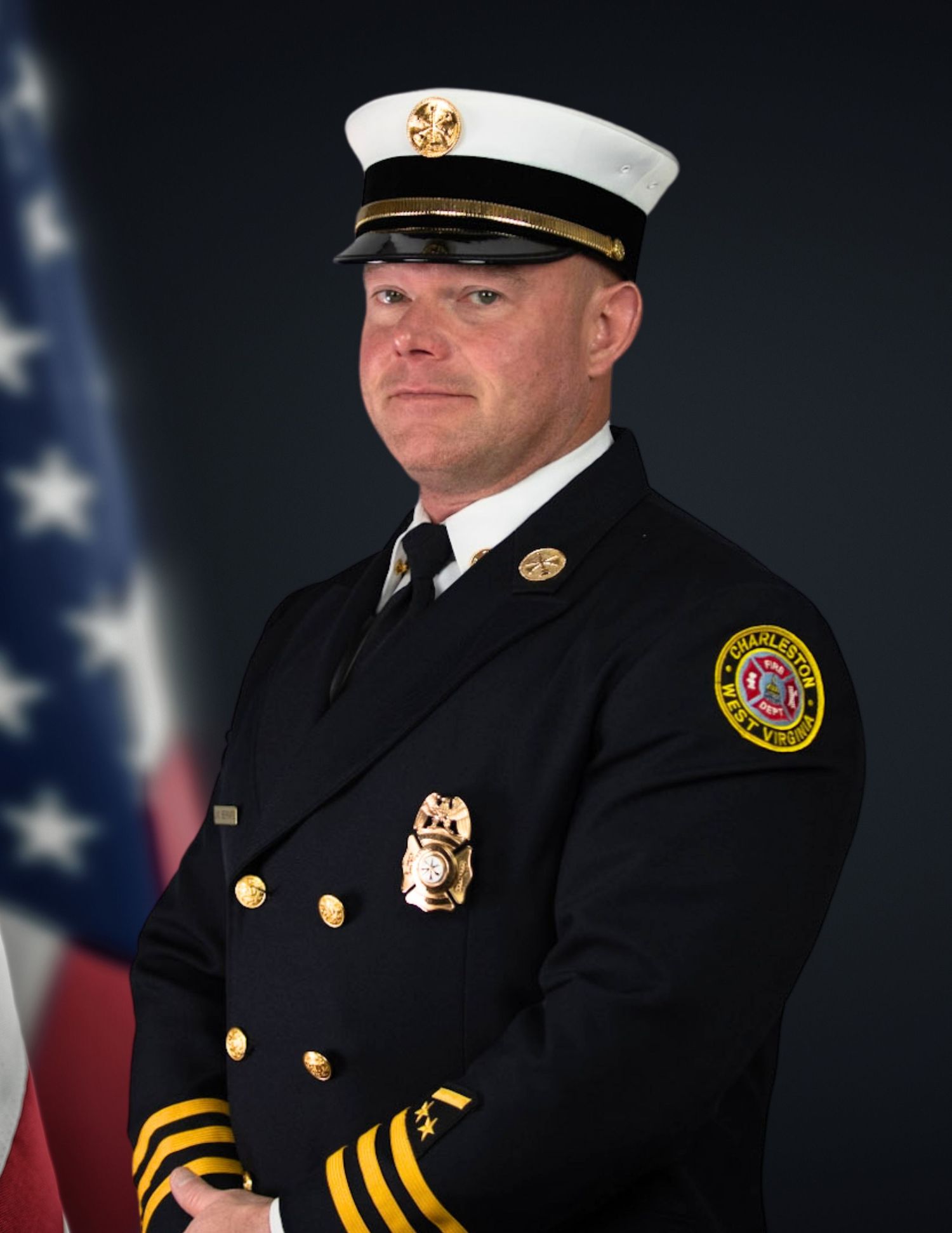 Firefighter poses in dress uniform with American flag background.