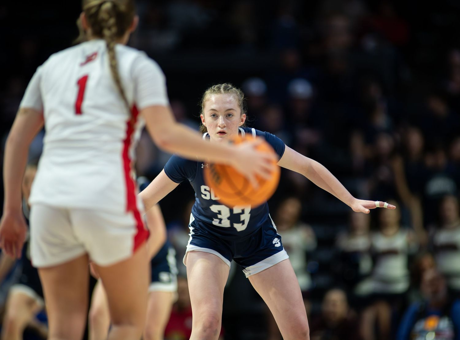 Volleyball players compete at the net during an intense match with one player preparing to spike the ball.