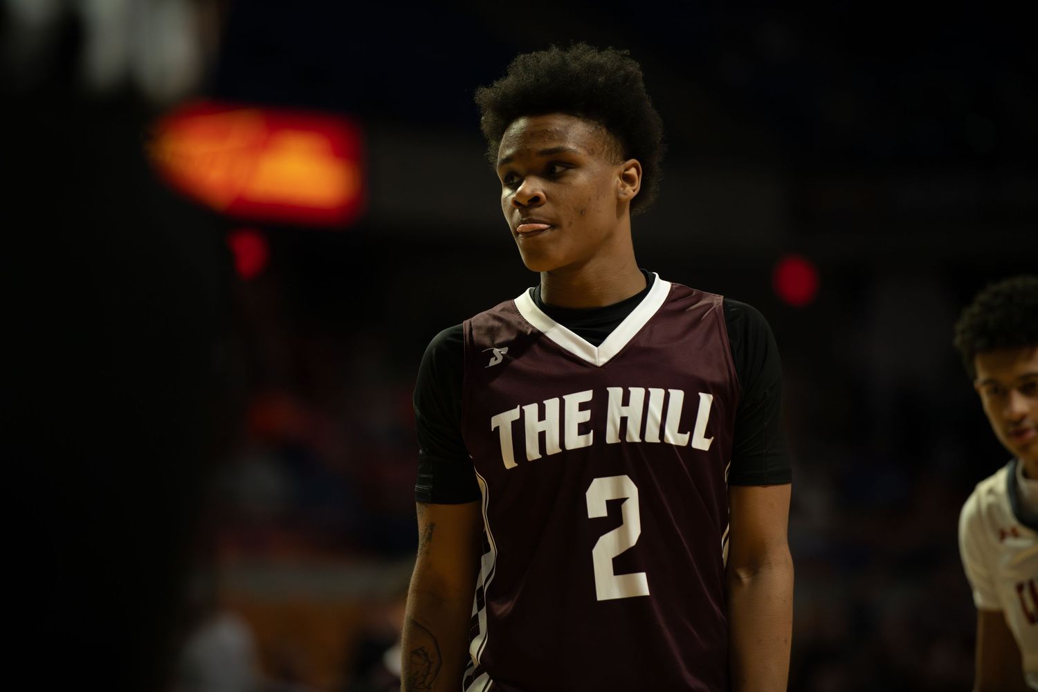 Basketball player in dark jersey stands on court during game.