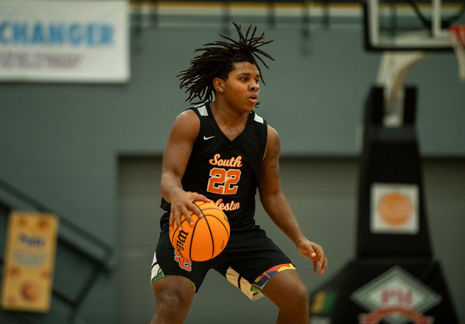 Basketball player in a black jersey dribbles down the court during an intense game.