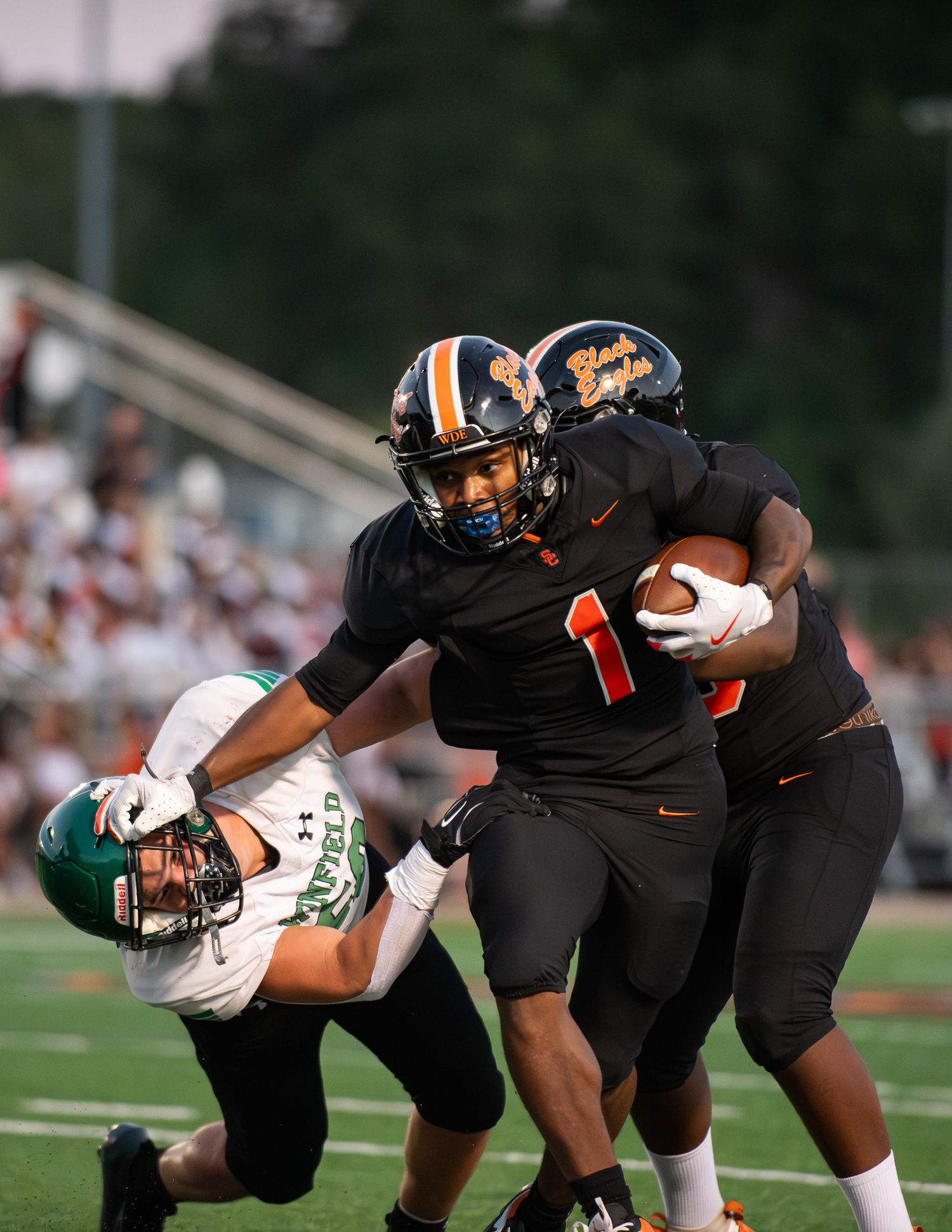 A sequence of football players in black uniforms making diving catches and tackles during a game.