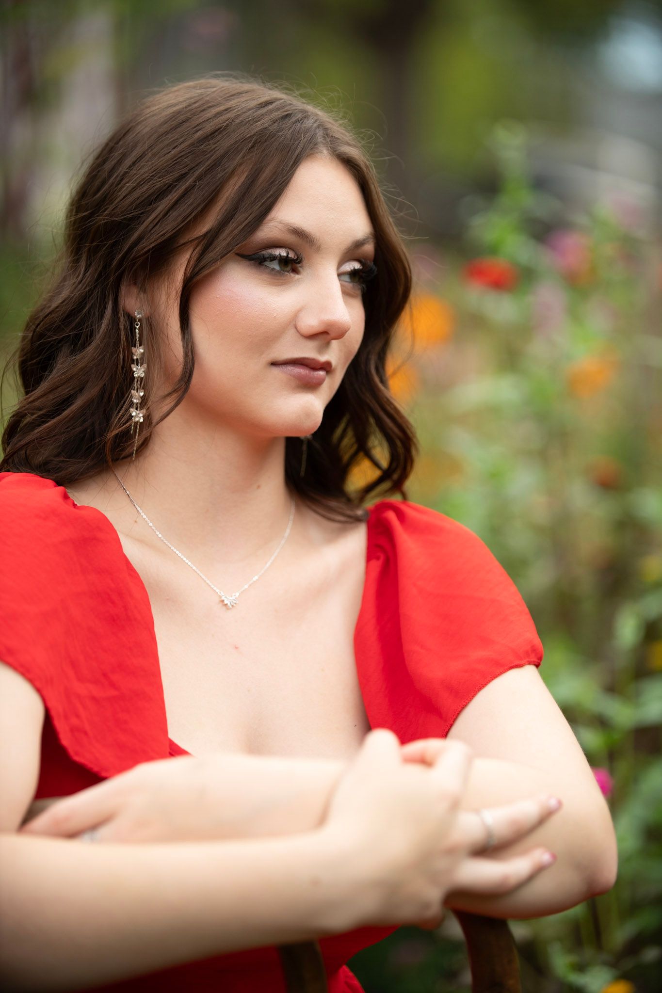 Outdoor portrait session featuring person in bright red dress against garden backdrop.