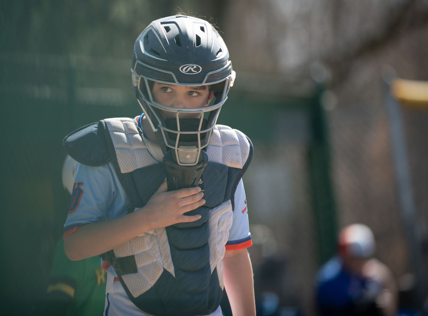 Young baseball catcher in protective gear and helmet during game.