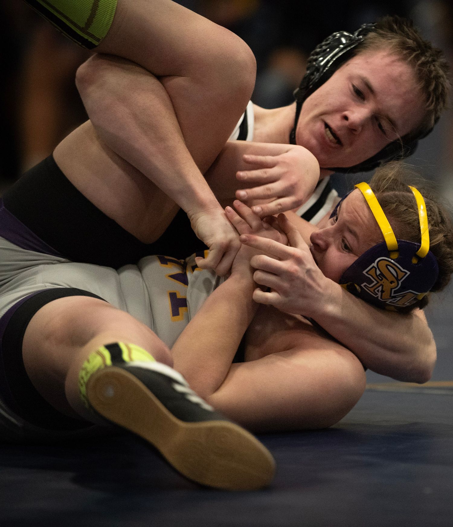 Two wrestlers grapple intensely during competitive match on mat.