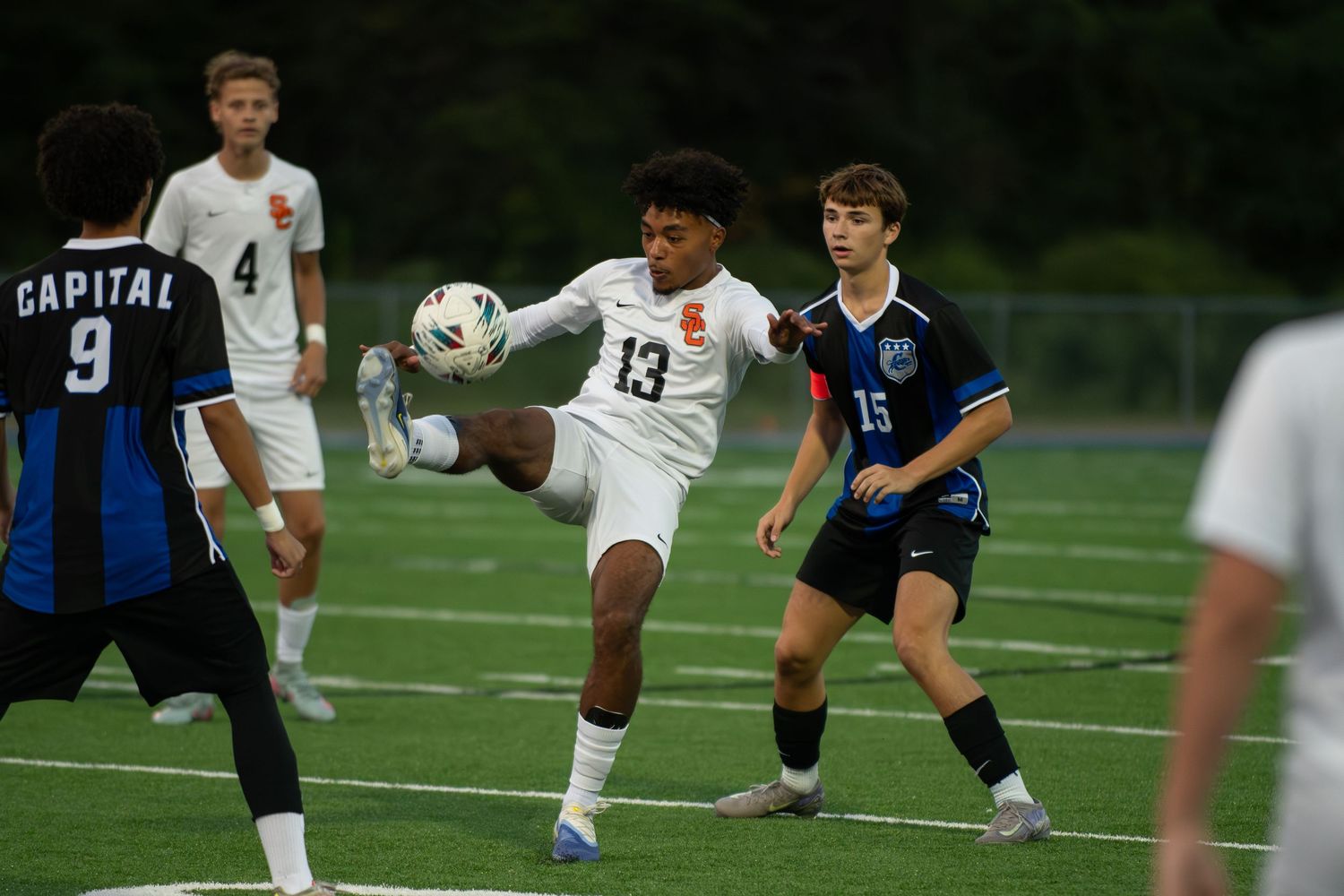 Soccer players compete for ball control during an intense match between teams in blue and white uniforms.