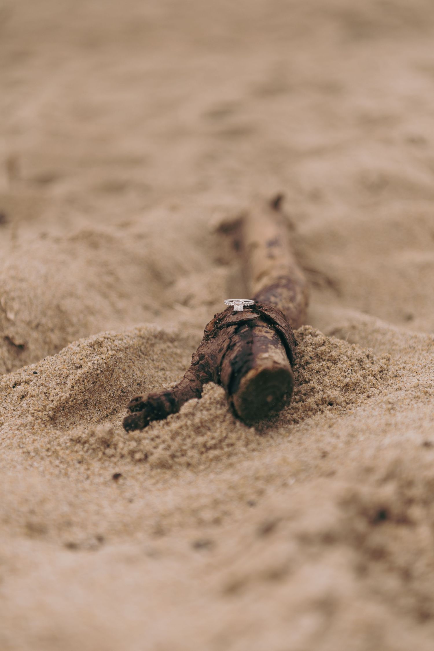A military action figure lies partially buried in sandy terrain with blurred background.