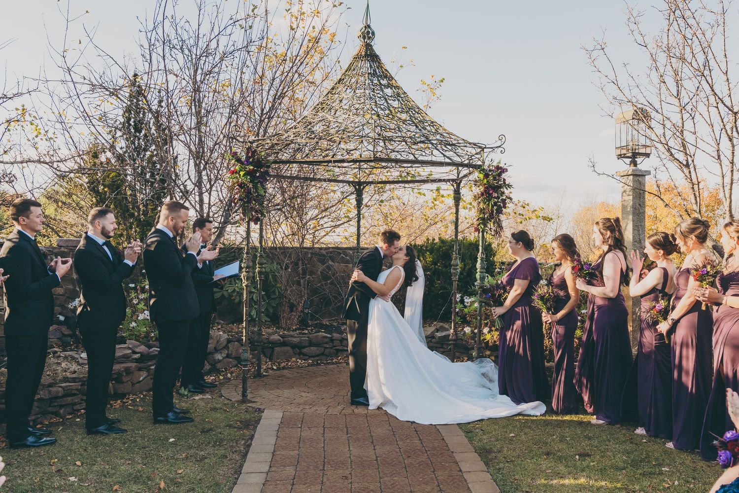 Outdoor wedding ceremony with guests seated in rows alongside vibrant fall foliage.
