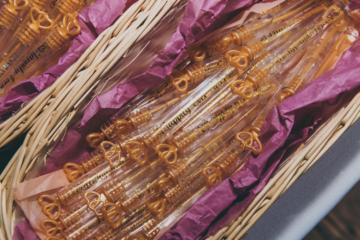 Rock candy crystals on wooden sticks nestled in purple tissue paper display a golden amber hue.