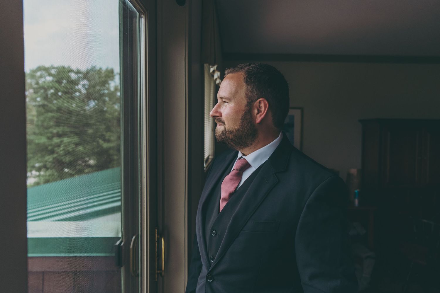 Side profile view of suited figure gazing thoughtfully out a window.