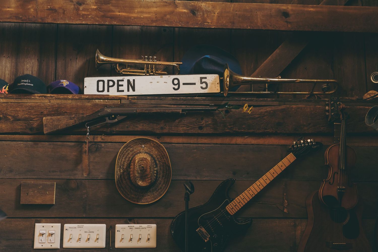 Vintage musical instruments and an open sign hanging on a rustic wooden wall.