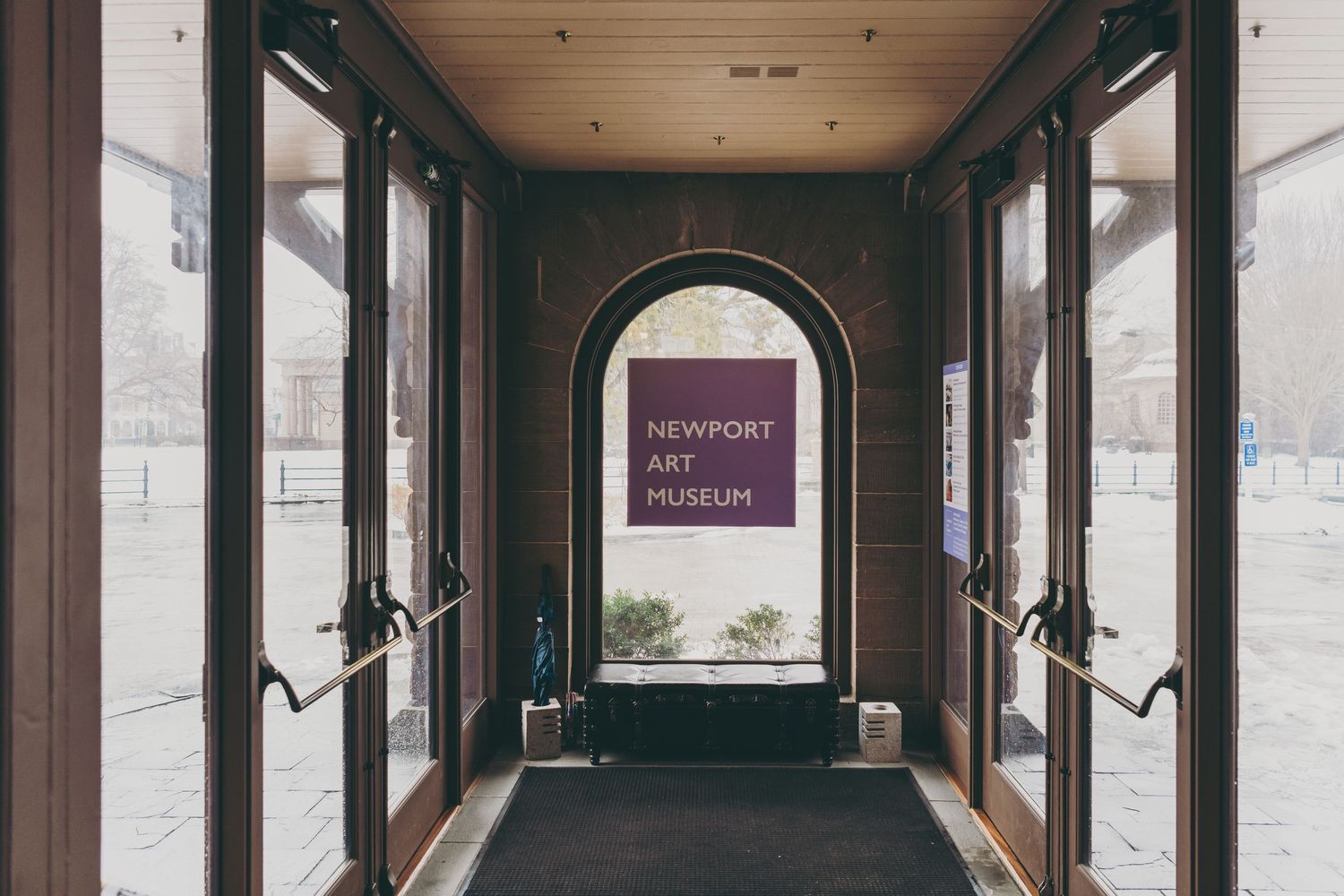 Modern entrance hallway with glass doors and purple signage mounted in an arched doorway.