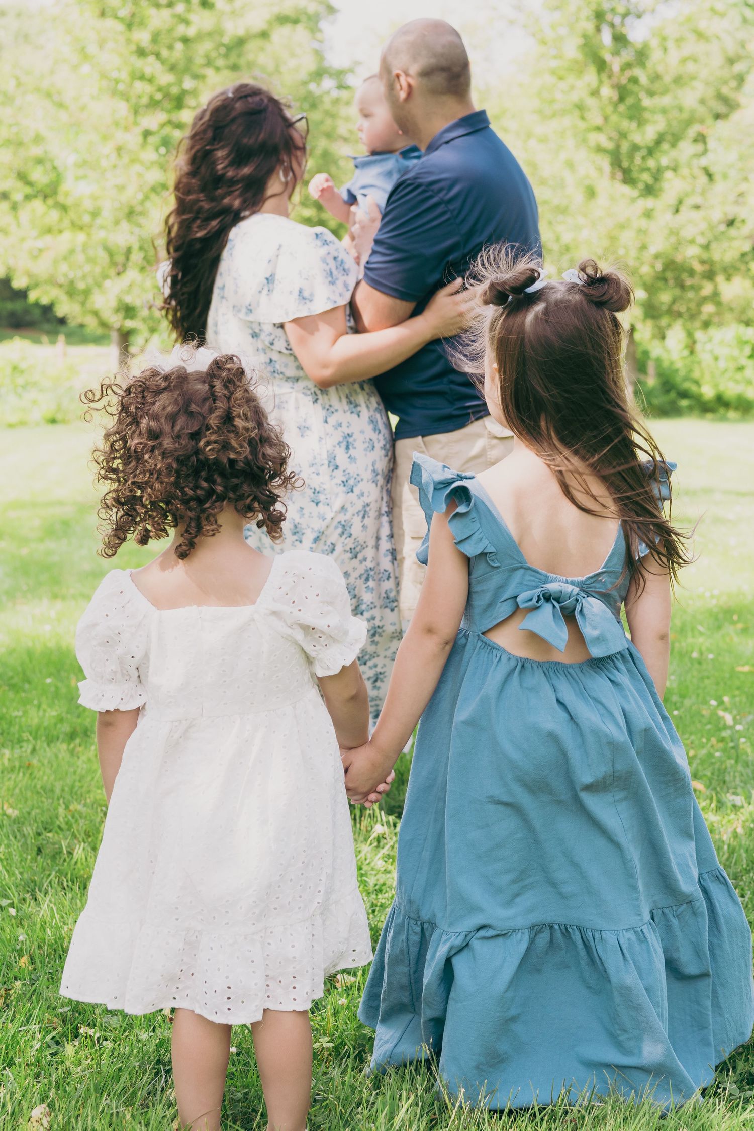 People gather on a grassy hill in blue and white dresses during a sunny summer day.