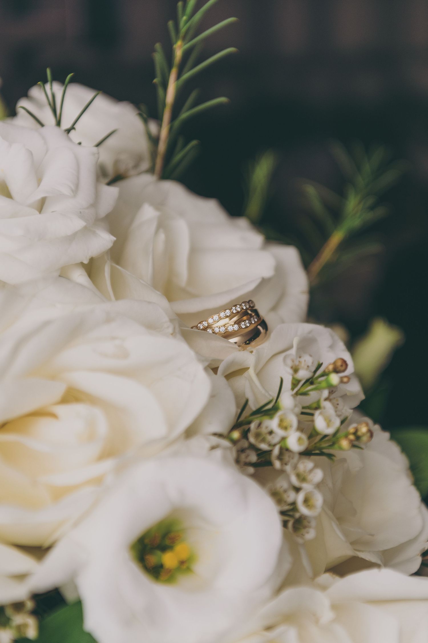 Wedding rings nestled among white roses and delicate floral arrangements.