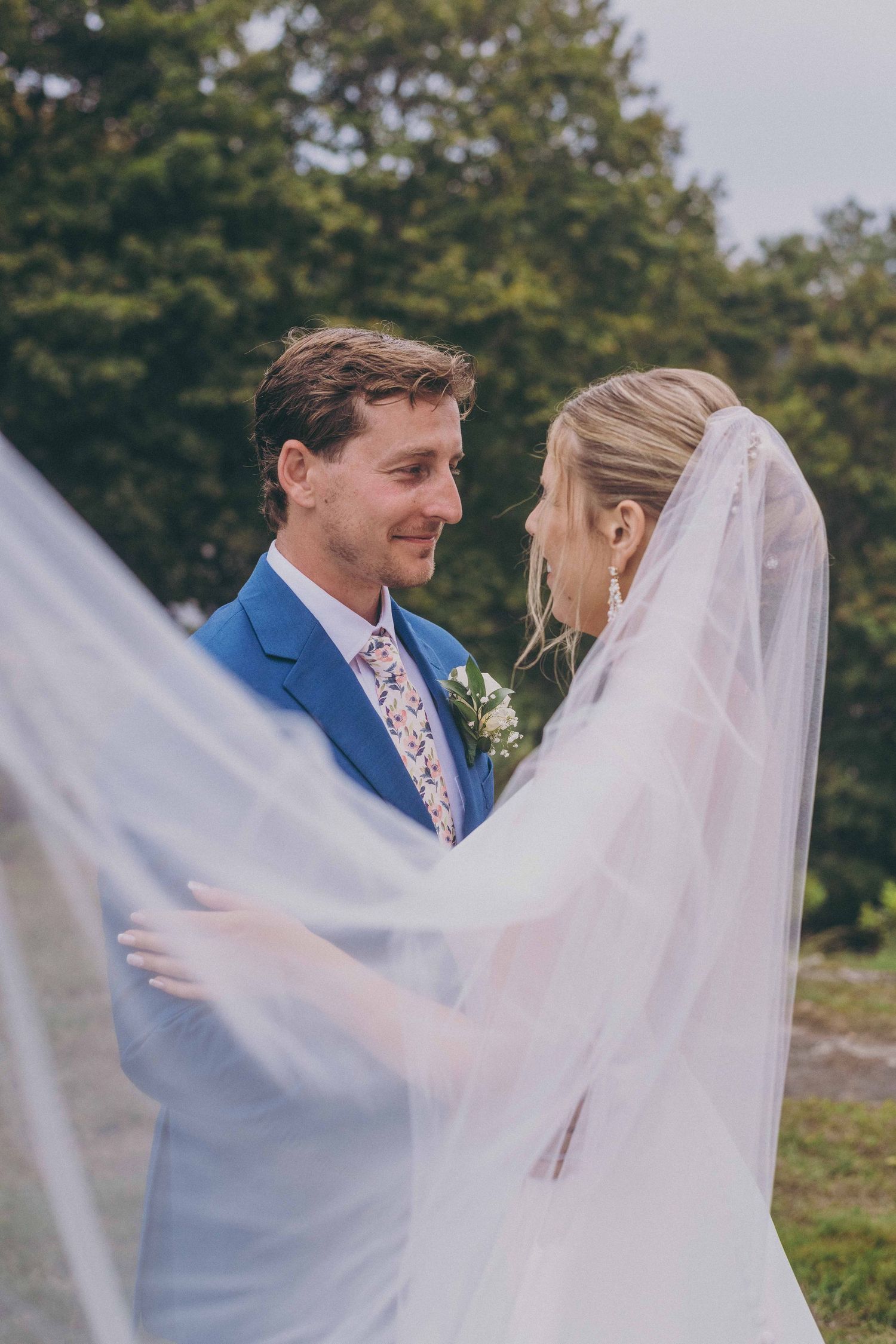 A couple shares an intimate moment during their outdoor wedding ceremony, with the bride's veil flowing in the breeze.