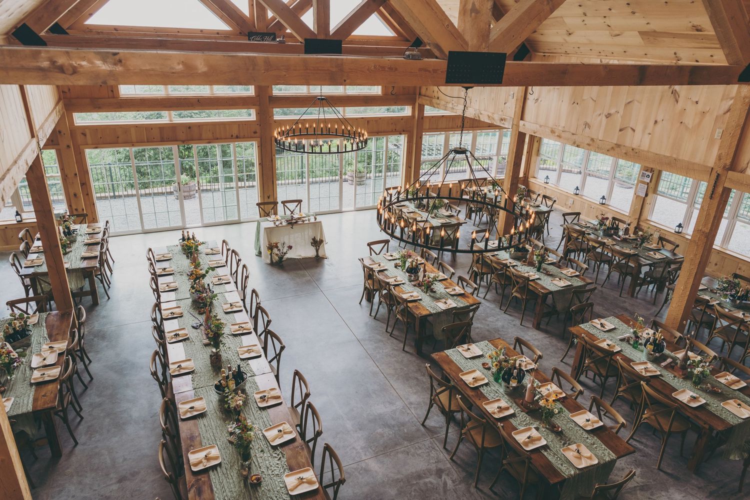 Rustic wooden banquet hall with exposed beams and elegant table settings for a wedding reception.