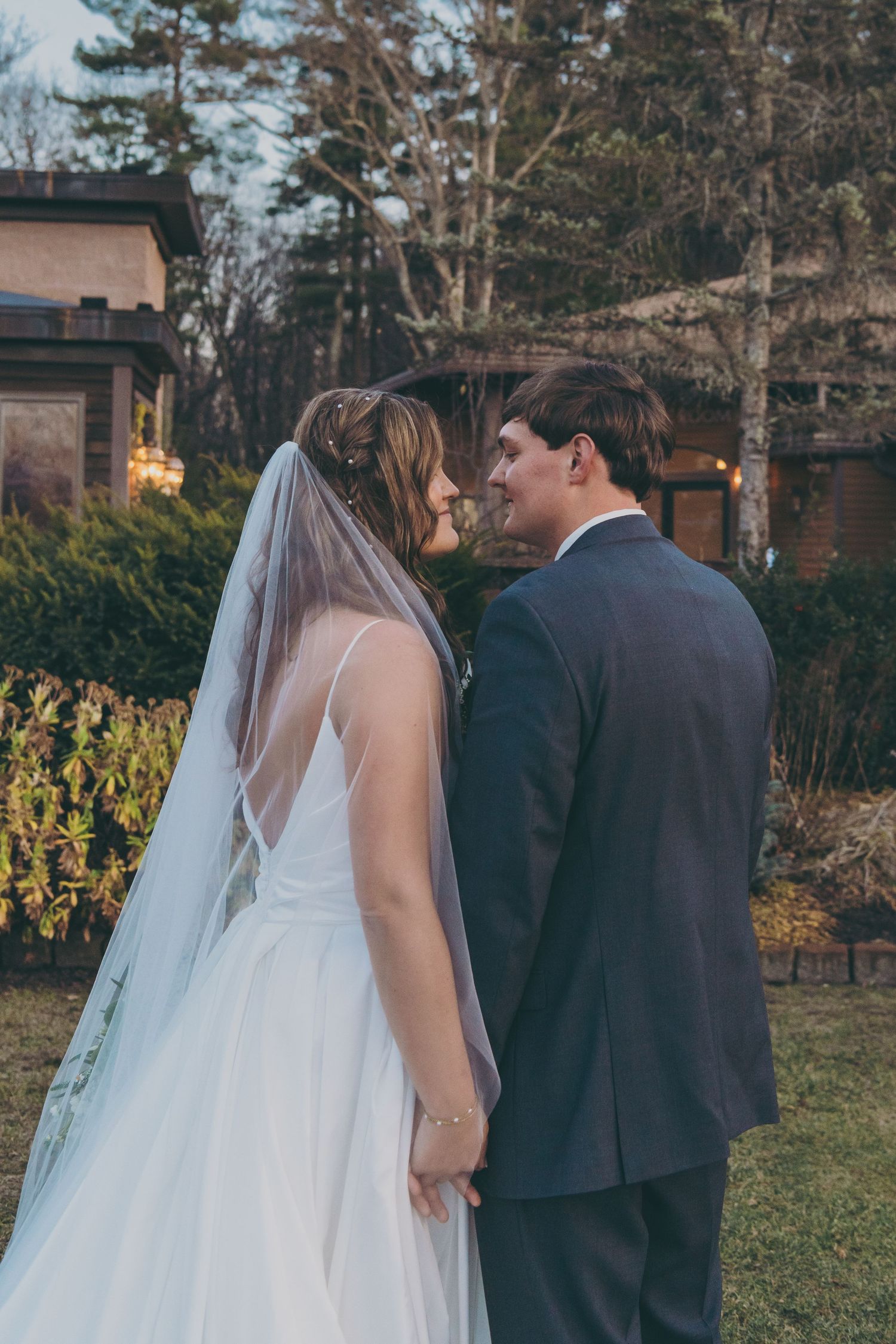 A couple shares an intimate moment at an outdoor garden wedding with the bride in white and groom in dark suit.