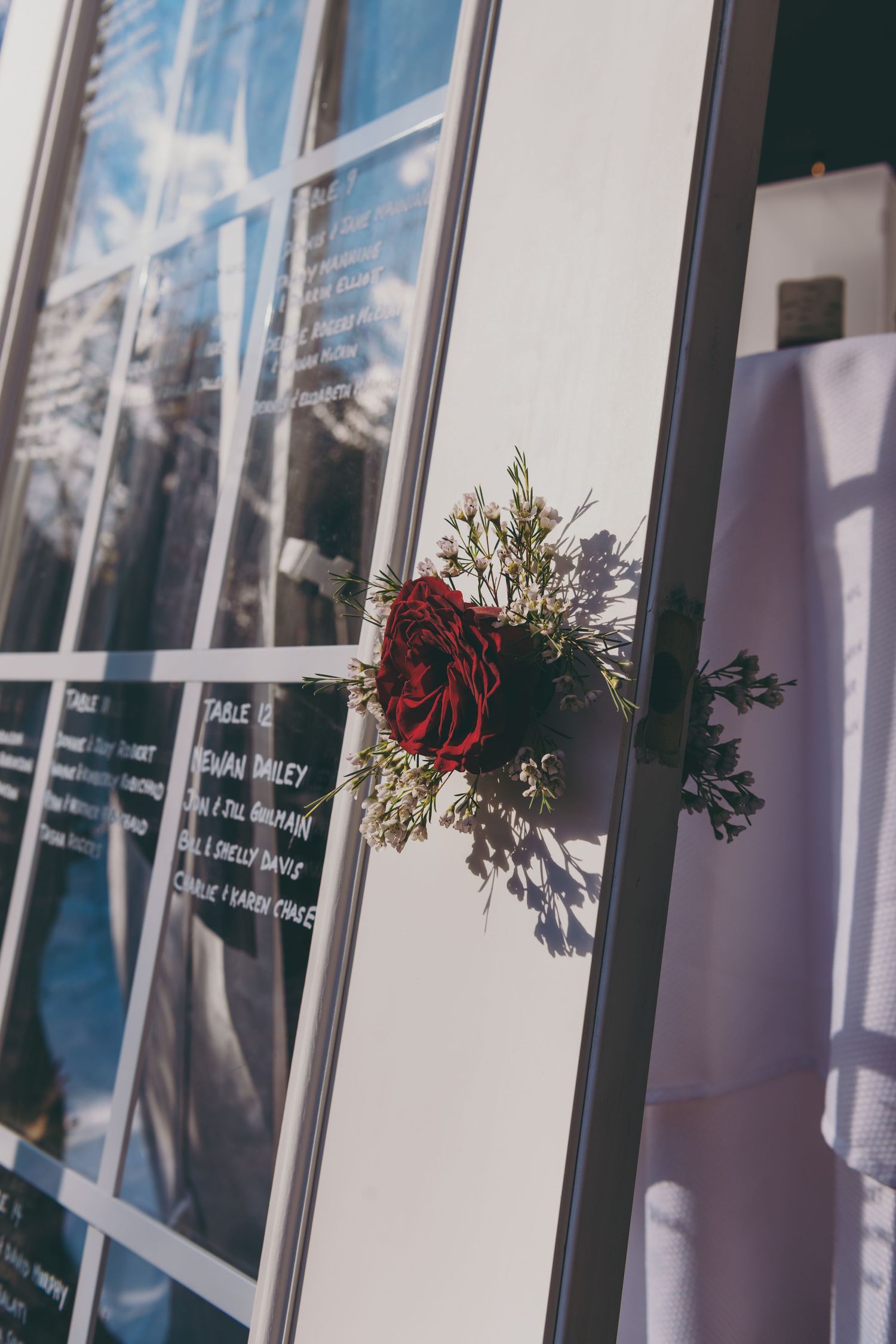 Red rose and greenery floral arrangement mounted on window frame.