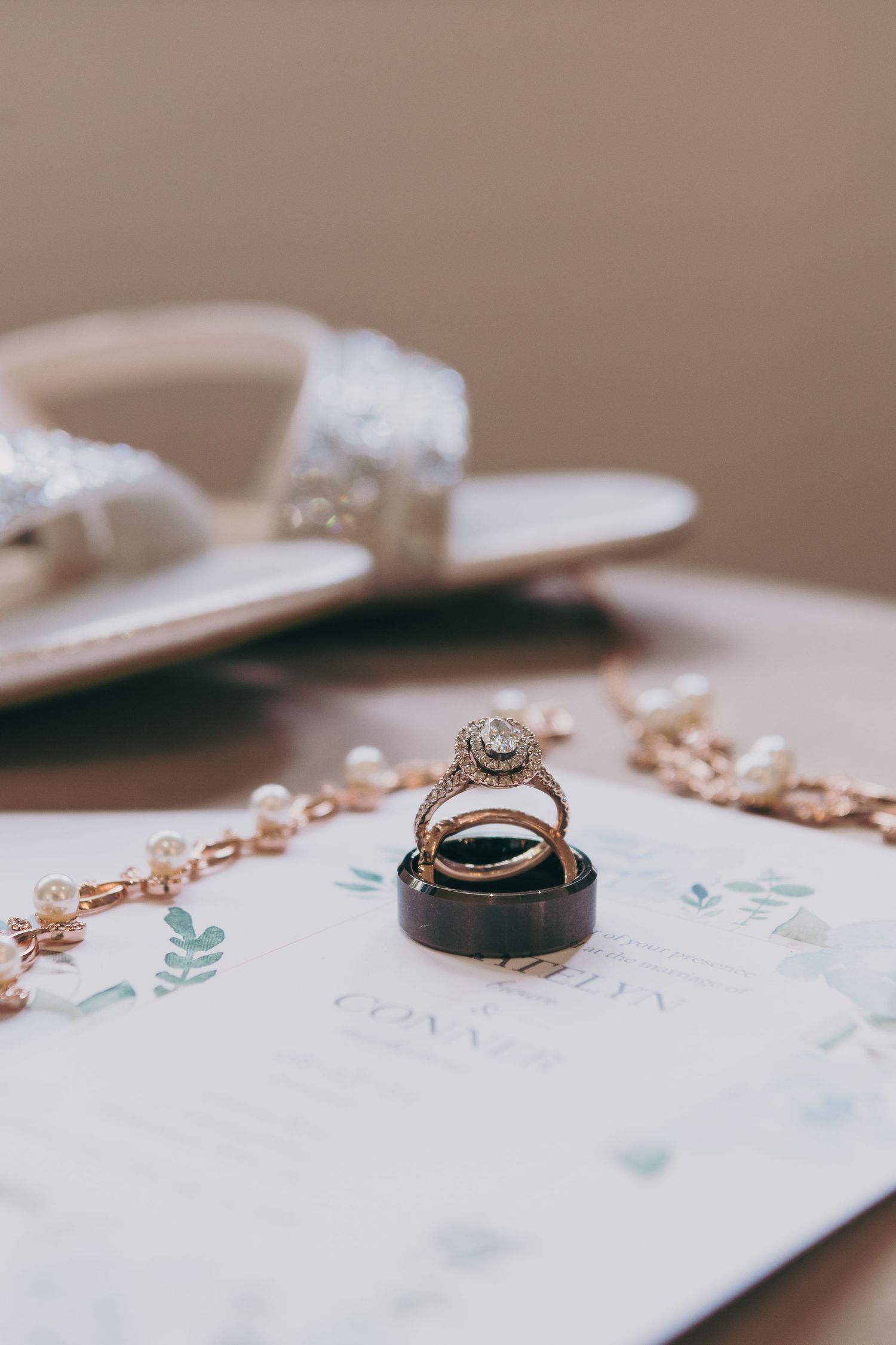 Fine jewelry detail shot showing wedding rings on a delicate floral patterned paper background.
