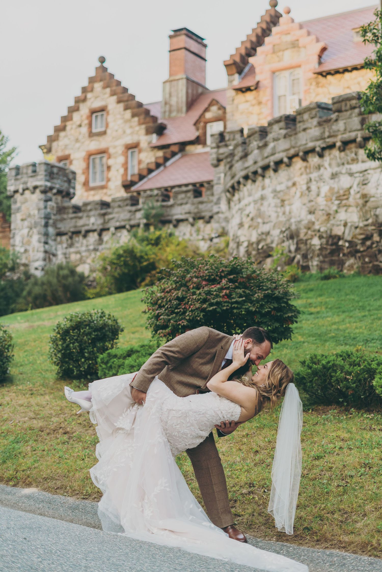 A romantic dip pose captured in front of a historic stone castle building.
