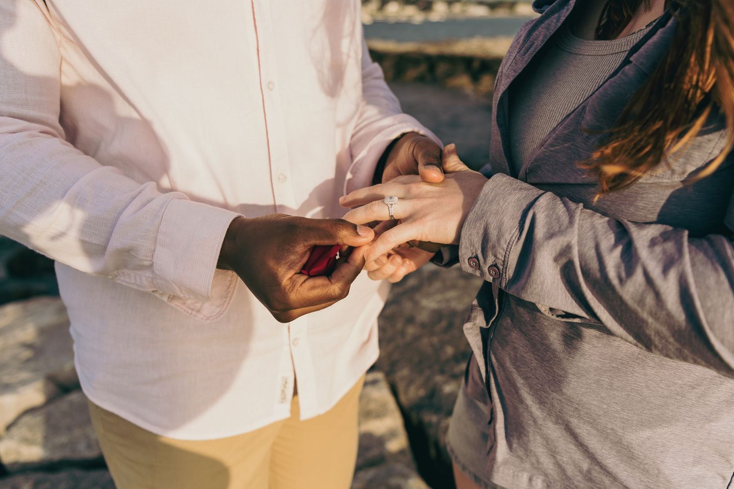 Two people sharing a close gentle moment holding hands together in warm sunlight.
