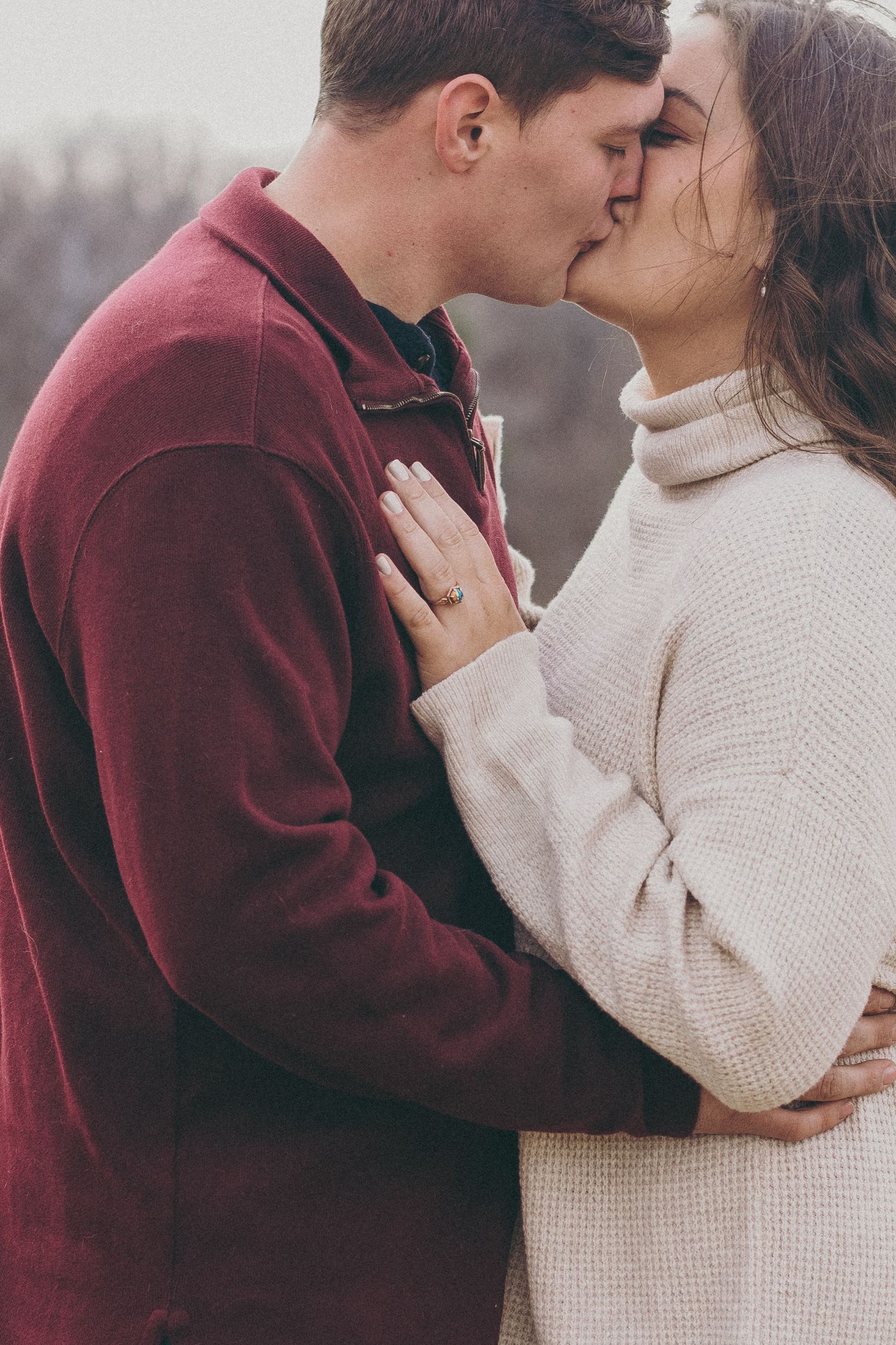 A couple shares intimate romantic moments in a series of photos wearing burgundy and cream colored winter clothing.