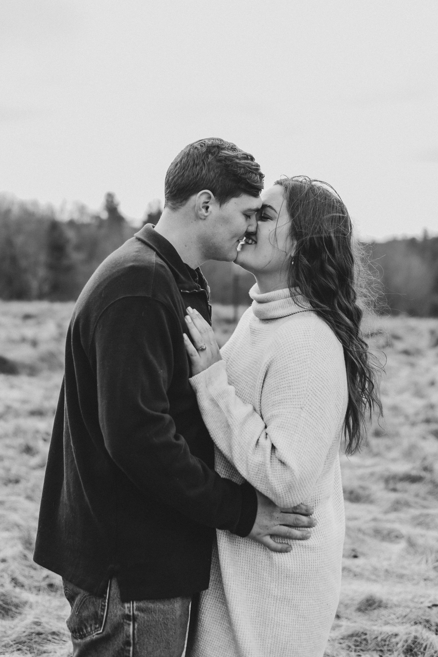 Intimate black and white portrait of couple in winter clothes sharing a tender moment outdoors.
