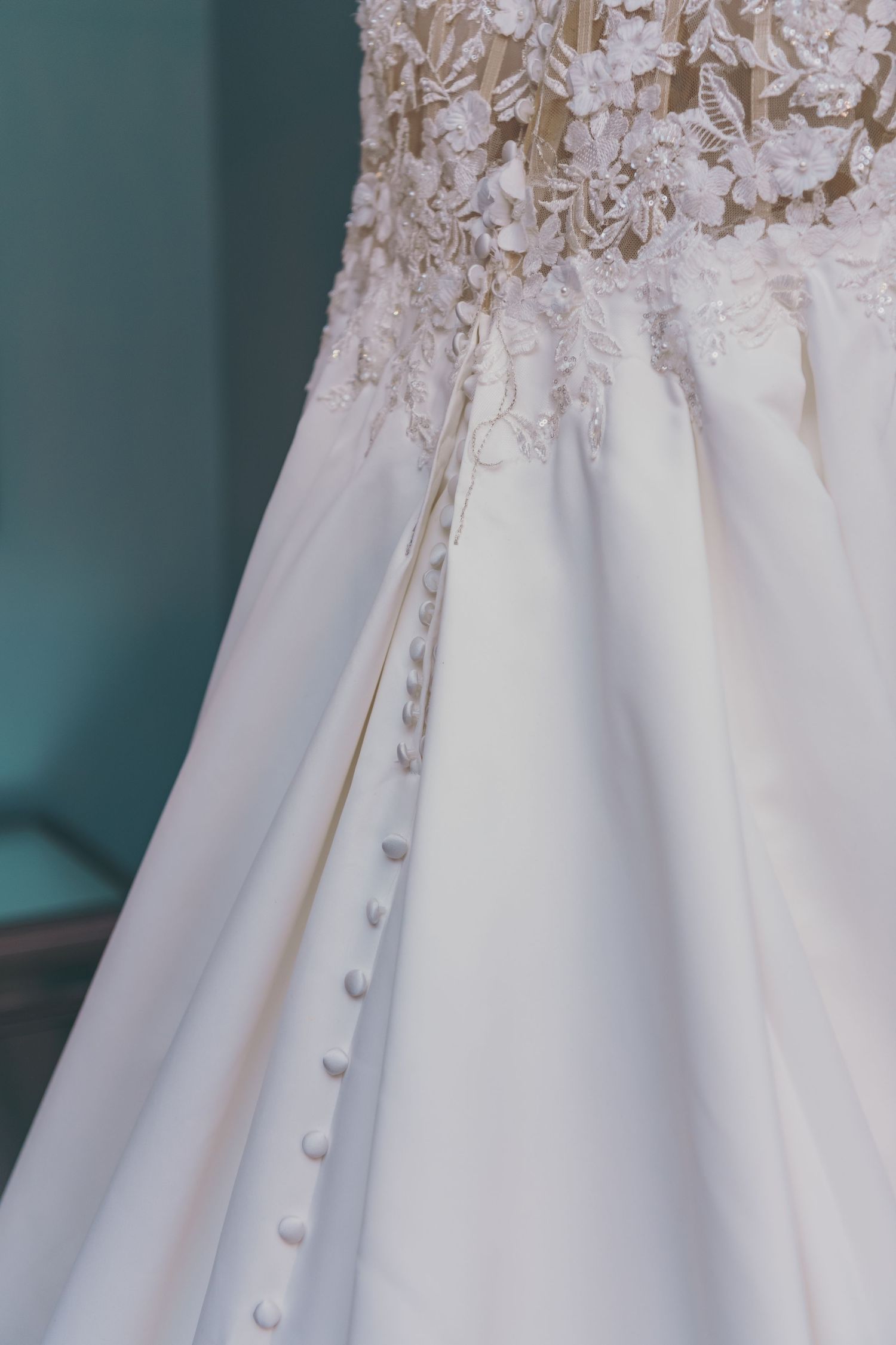 Wedding dress's continuous row of covered buttons adorning the back, creating an elegant detail on white fabric.