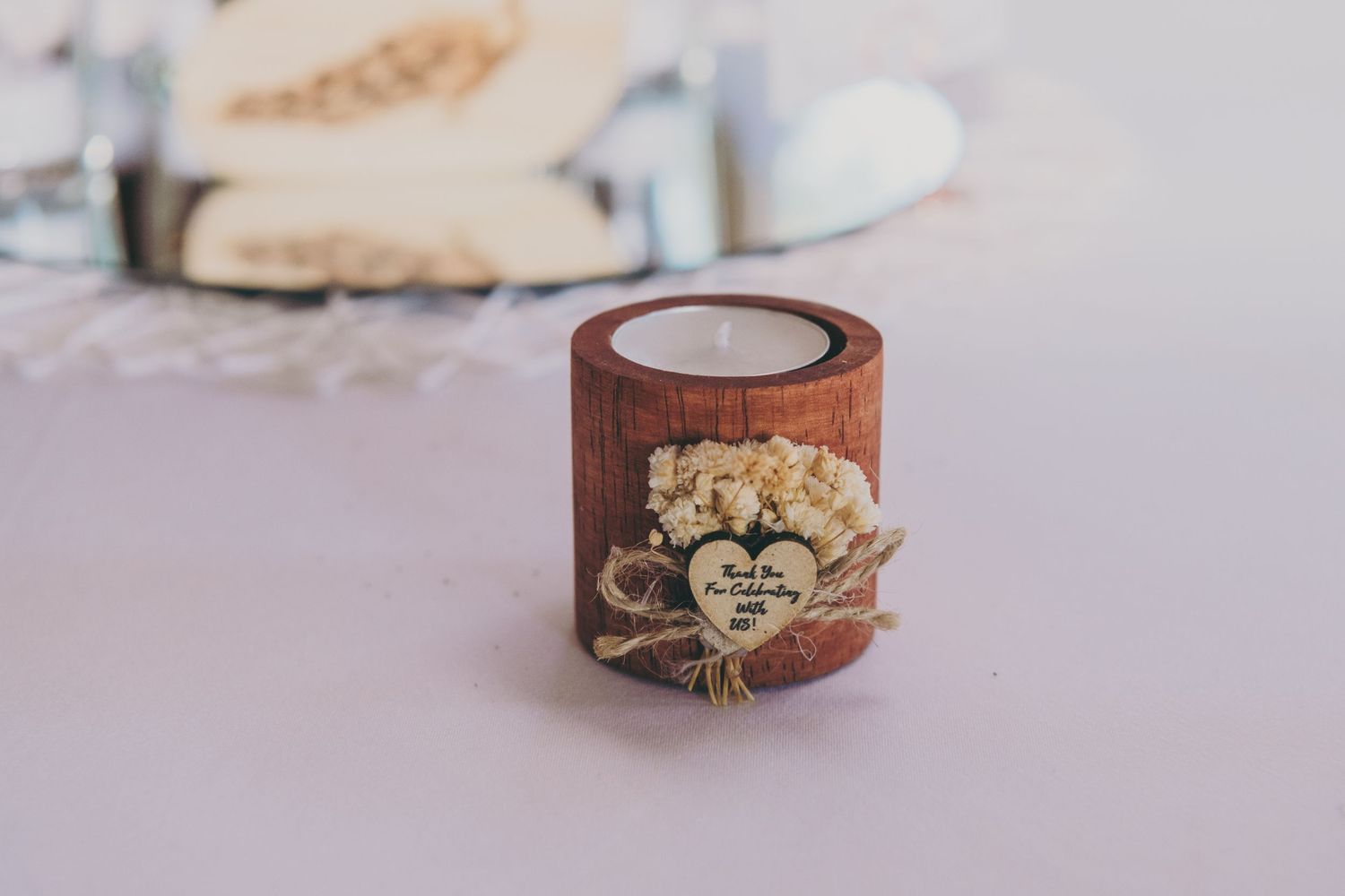 Small wooden candle holder decorated with vintage floral embellishment sits on light purple surface.
