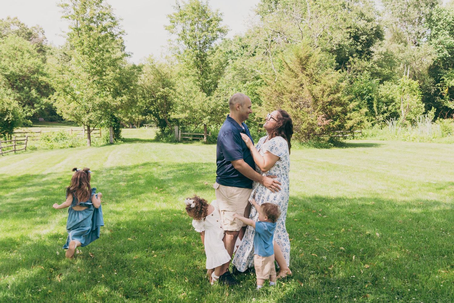 A family gathering in a sunny park with children playing around their parents.