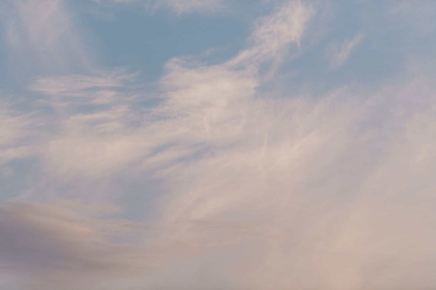 Soft wispy clouds create delicate patterns against a pastel pink and blue sky at sunset at Scituate Lighthouse.