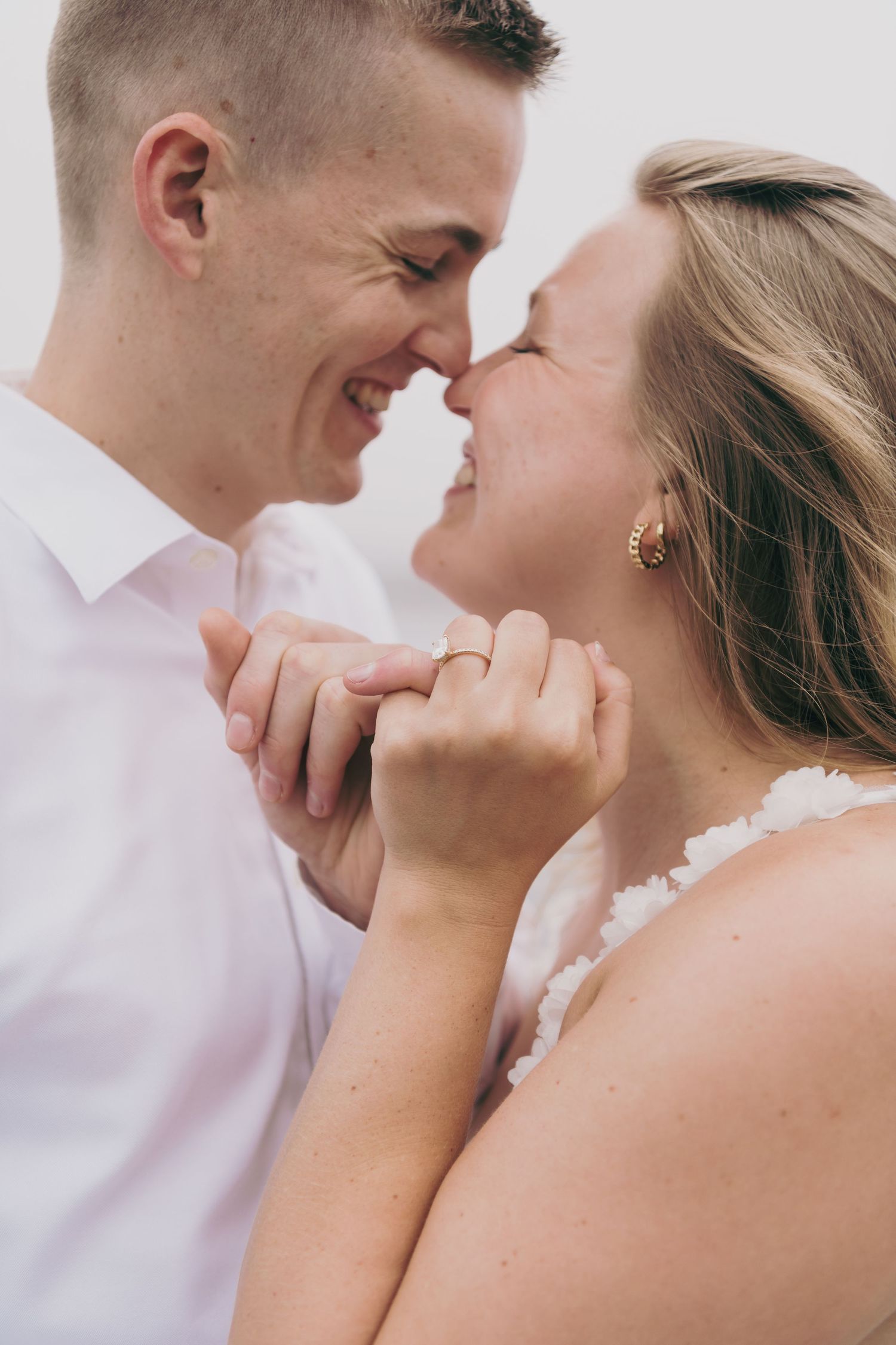 Close up romantic portrait of a couple sharing an intimate moment in white attire.