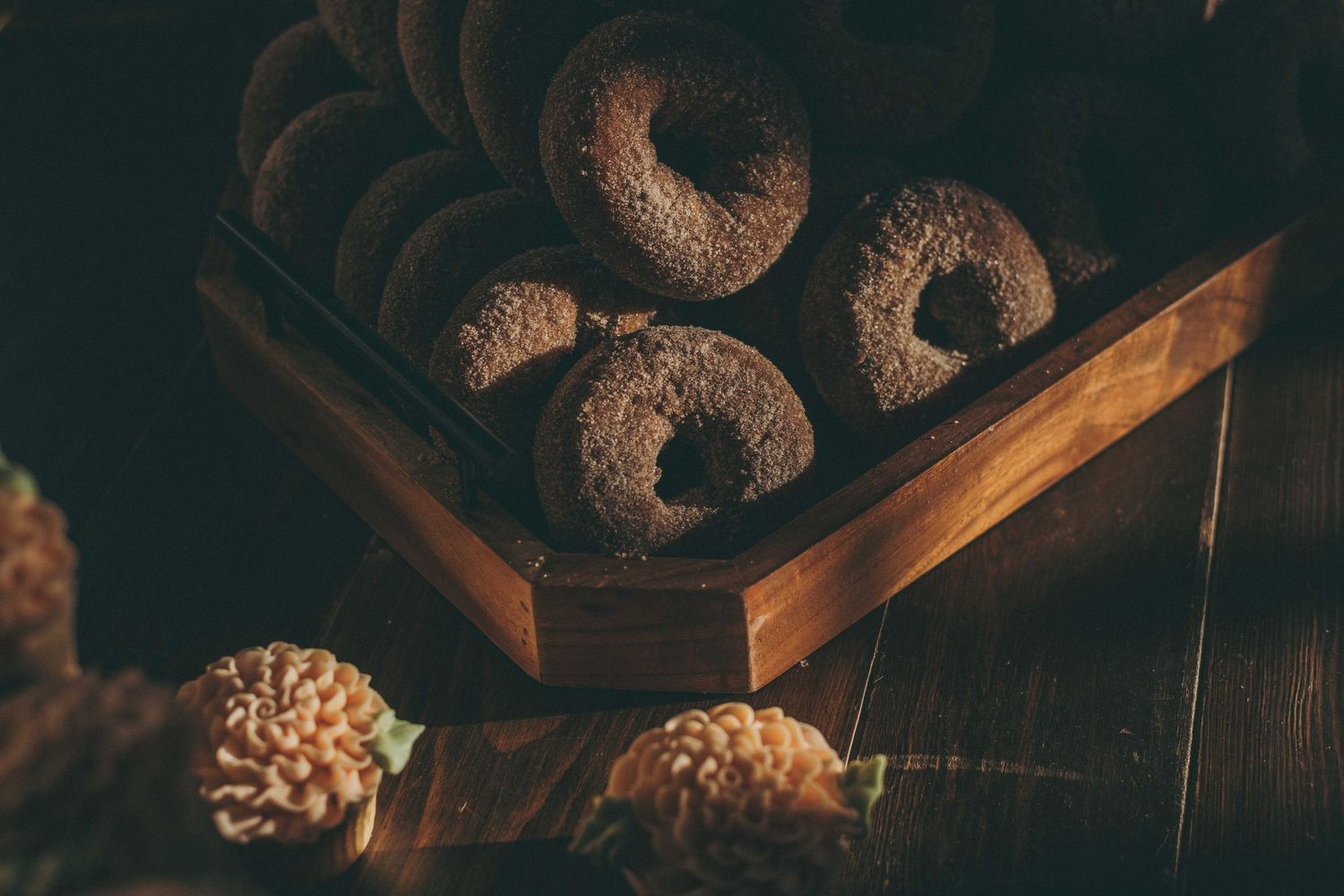 Chocolate coated crescent cookies with powdered sugar arranged in a dark wooden box on rustic wooden surface.