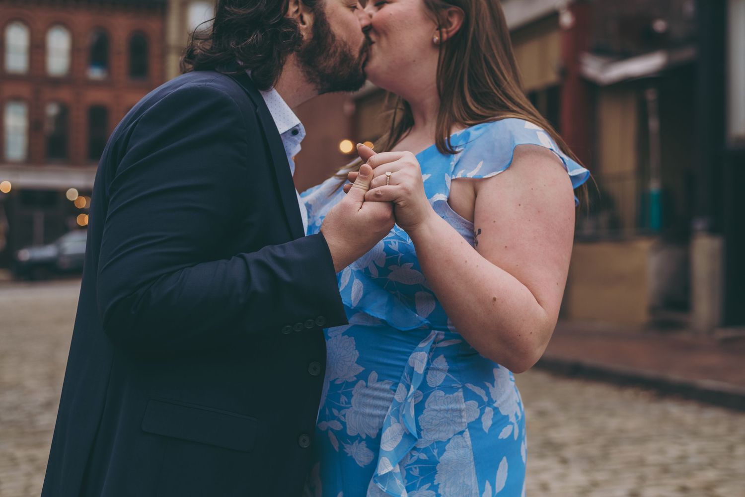A couple embraces in a romantic dance pose on a cobblestone street surrounded by historic architecture.