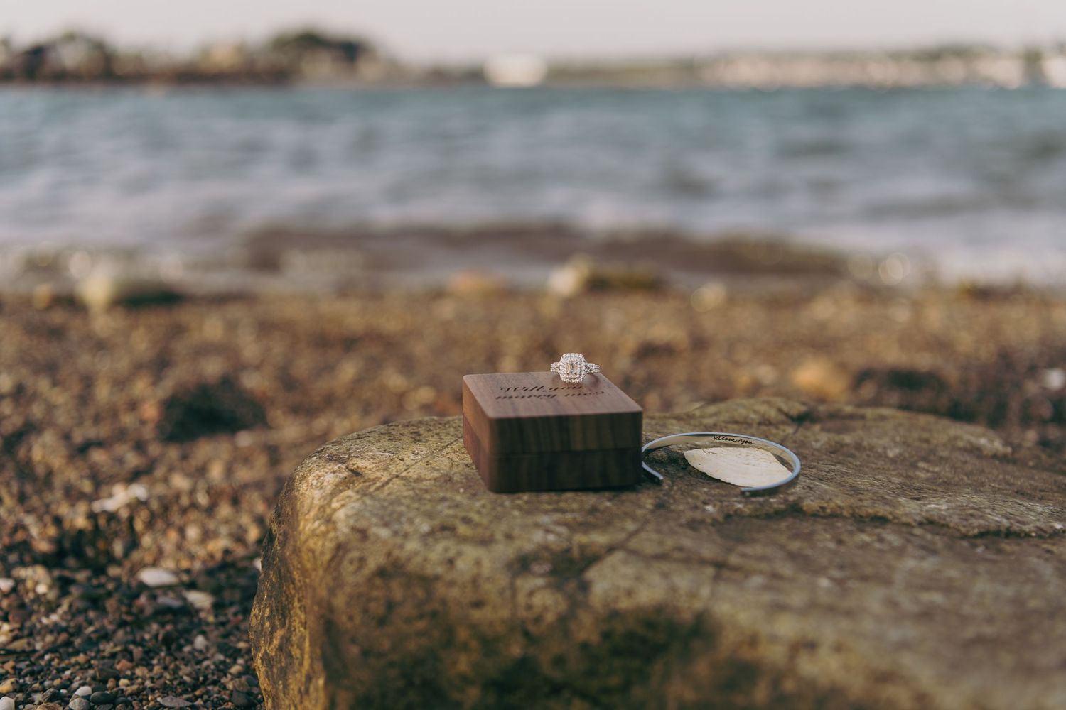 Sandy beaches and rocky shoreline with crashing waves against stone during sunset on an empty beach.