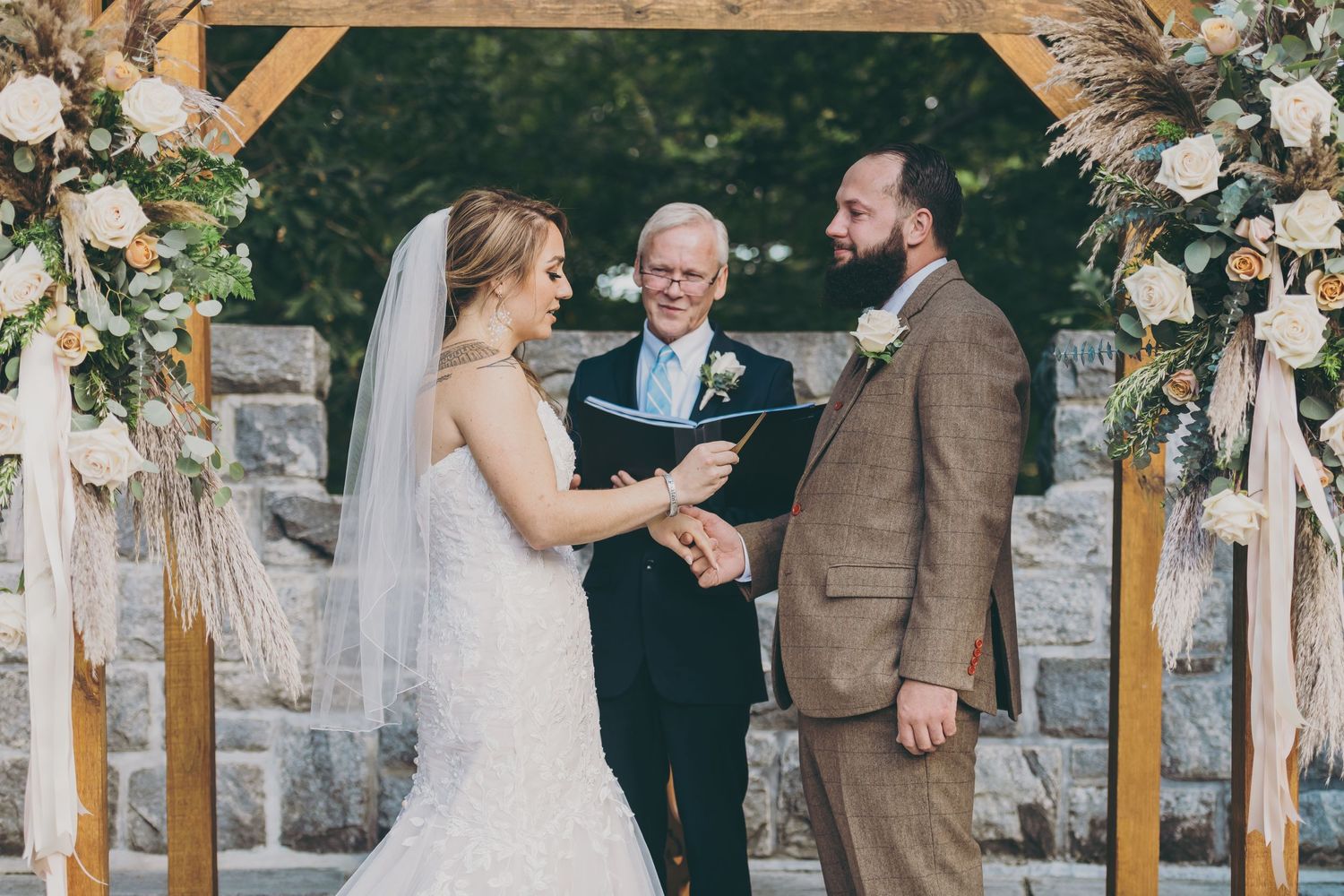 A wedding ceremony takes place under a wooden arch at Searles Castle.