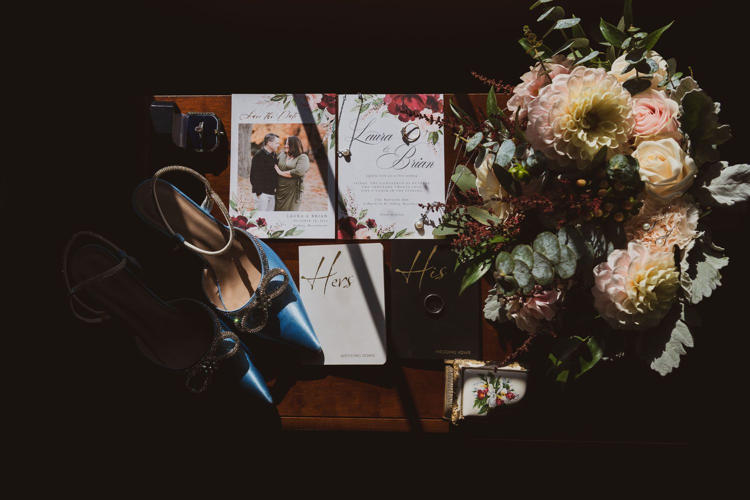 Wedding details including invitations and floral arrangements captured in dark, moody lighting.